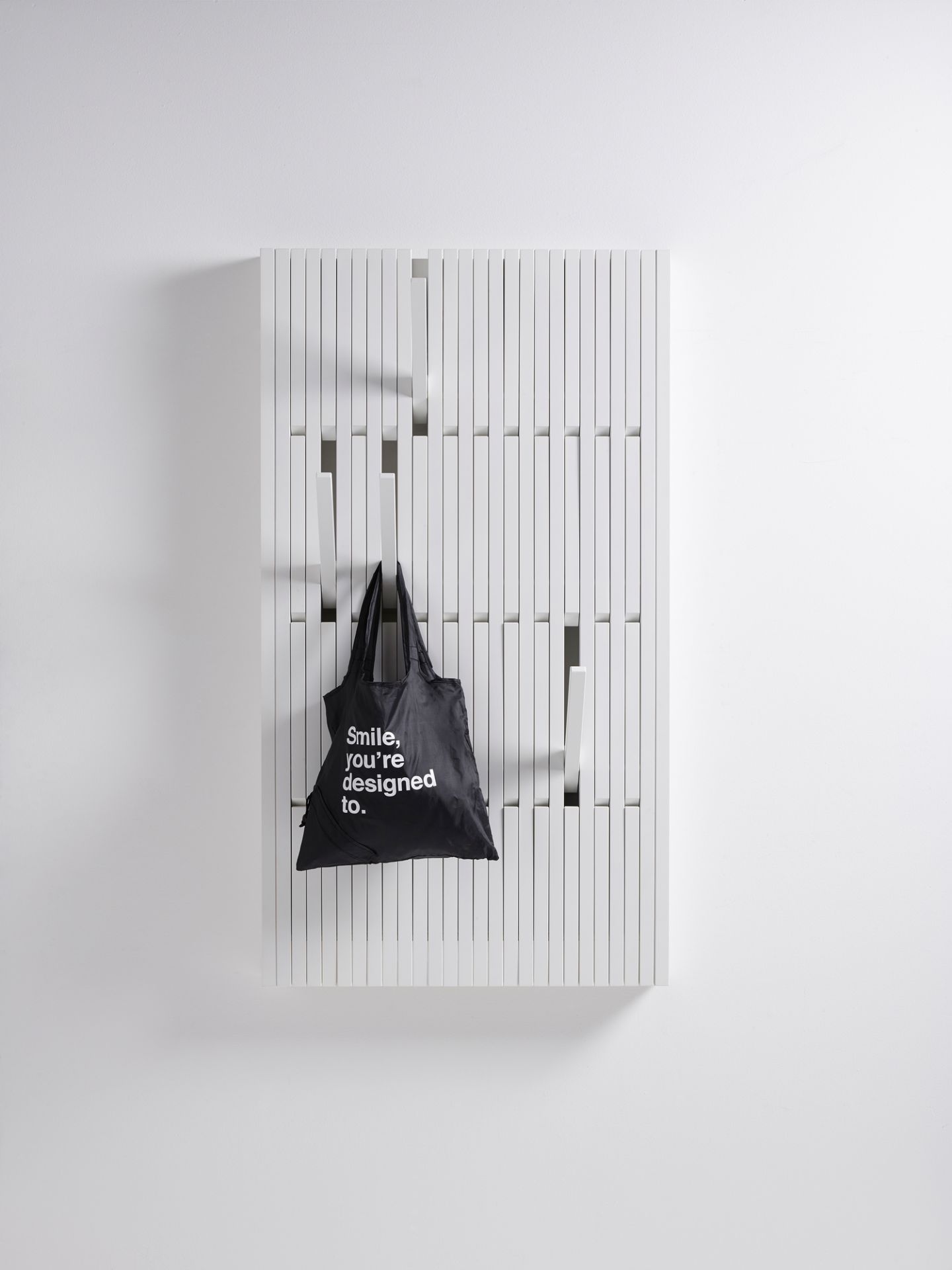 Weiße Piano Wandgarderobe mit schwarzer Stofftasche als Beispiel für die Nutzung. Design Garderobe.