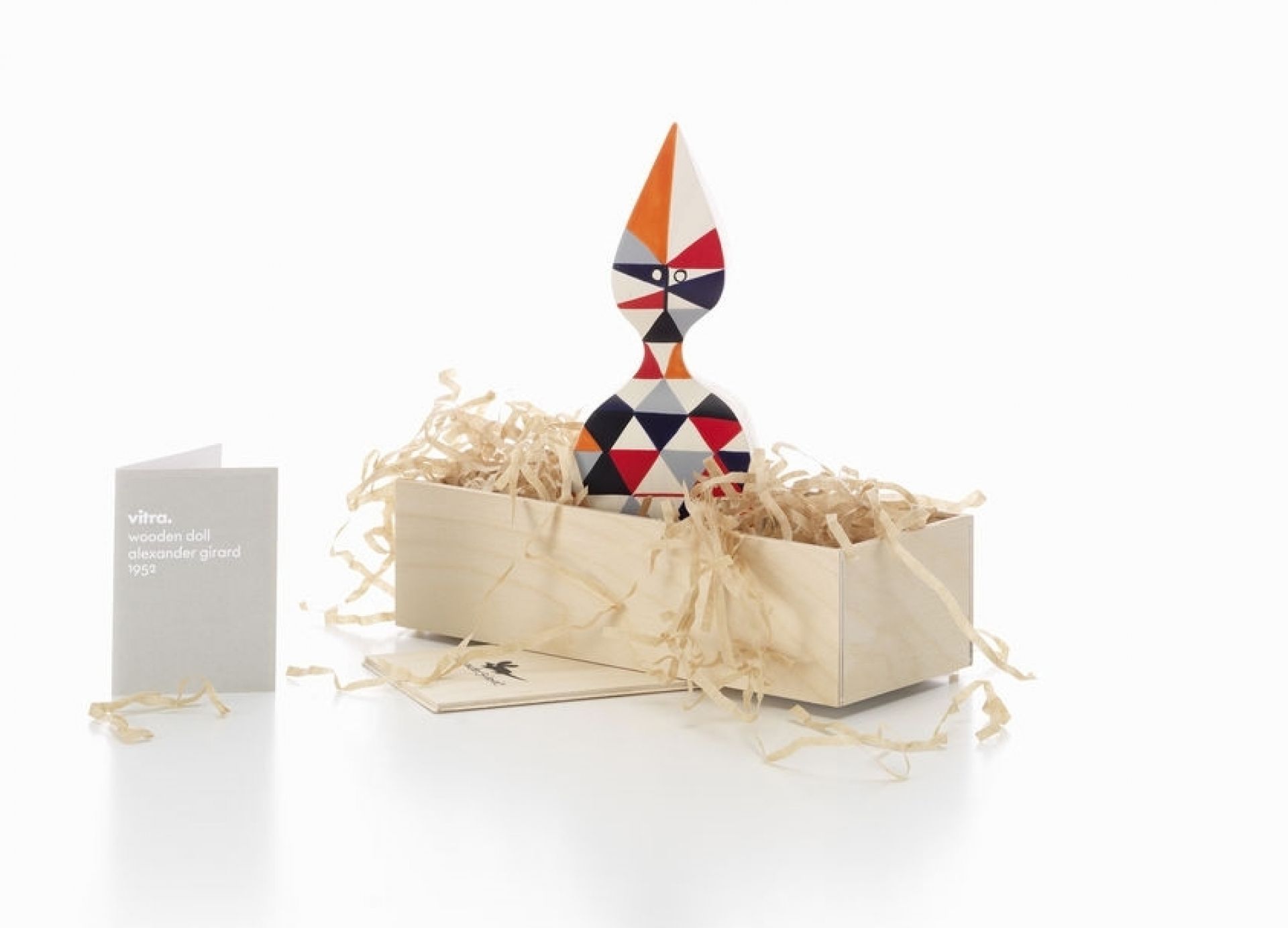 Vitra Wooden Doll No. 12 Holzfigur in Holzkiste mit buntem geometrischen Muster.