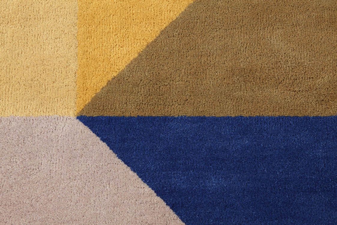 Detailansicht des Zoe Kubb Teppichs mit geometrischem Muster in Gelb, Braun, Beige und Blau.