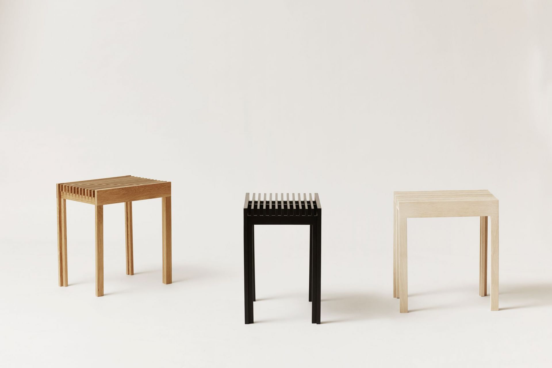 Drei Form & Refine Lightweight Hocker aus Eiche, natur, schwarz gebeizt und hell, auf weißem Grund.