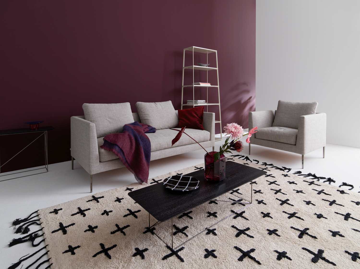 Helles Sofa ohne Rückenkissen, Modell Pilotis, mit Sessel und Teppich im Wohnzimmer.