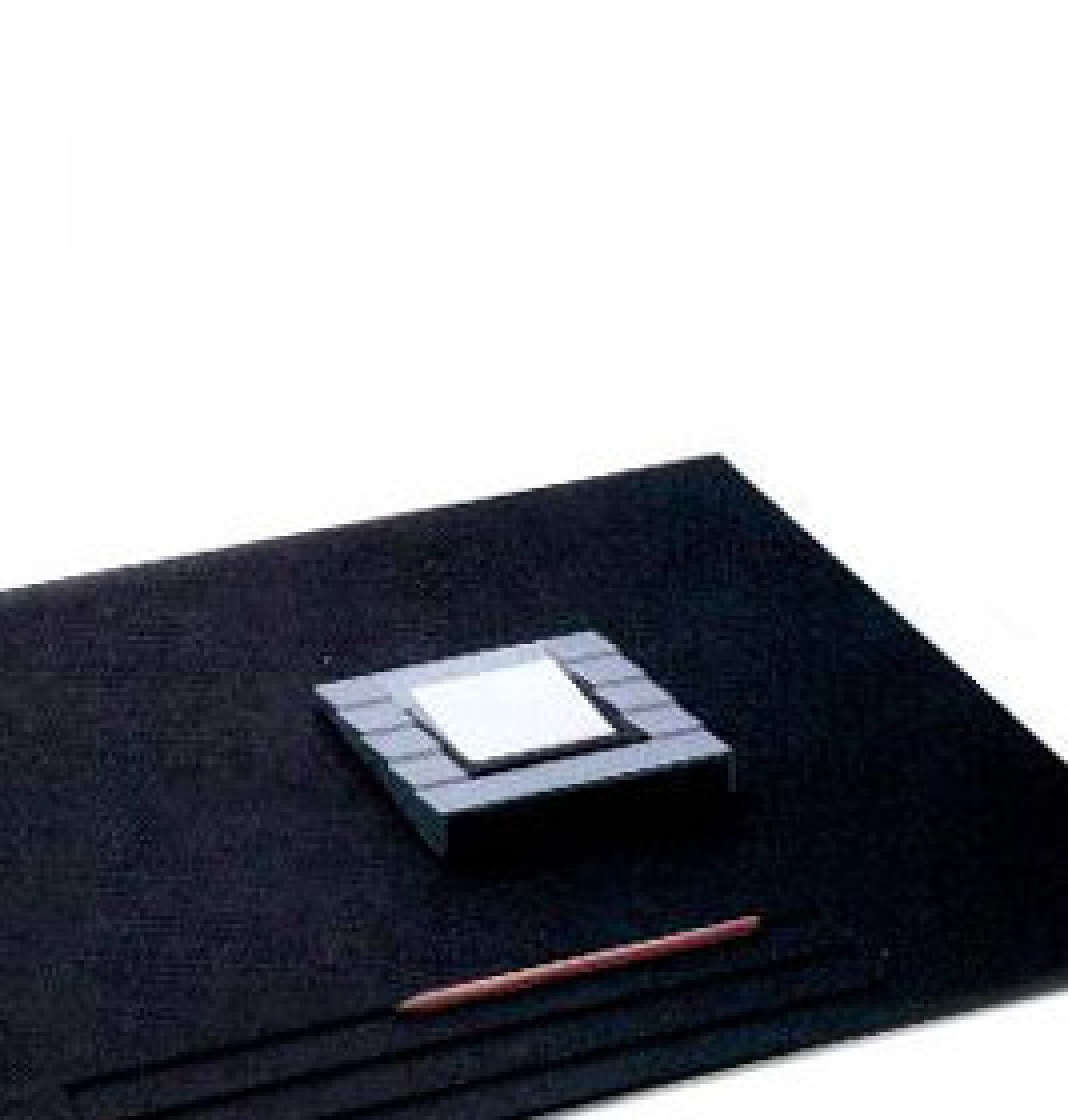 Quadratische, graue Zettelbox (Rexite Status) auf schwarzem Untergrund mit Stift. Büroaccessoire für Notizen.