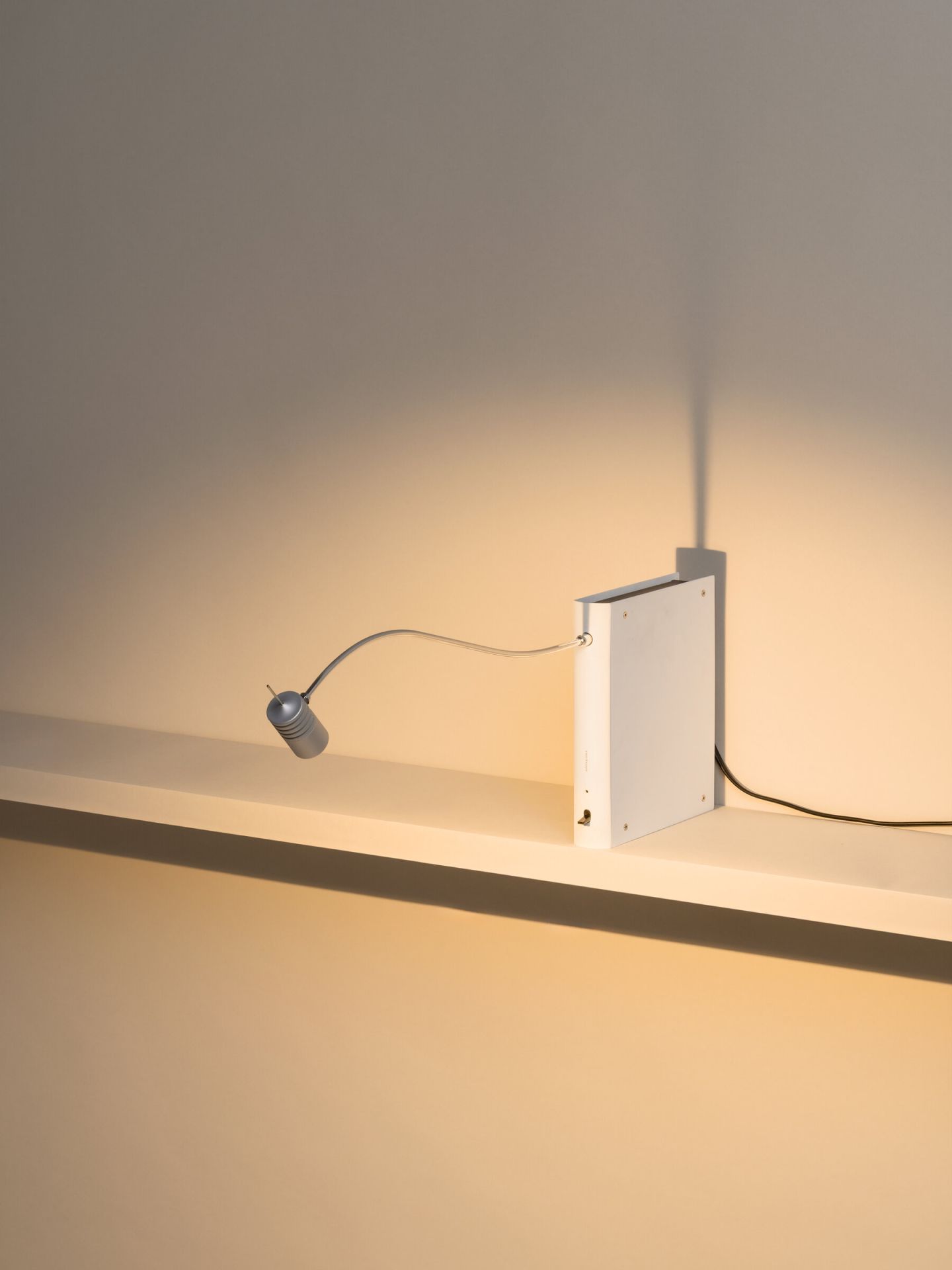 Bib Luz Tischleuchte von Santa & Cole in Off White auf einem Regal.