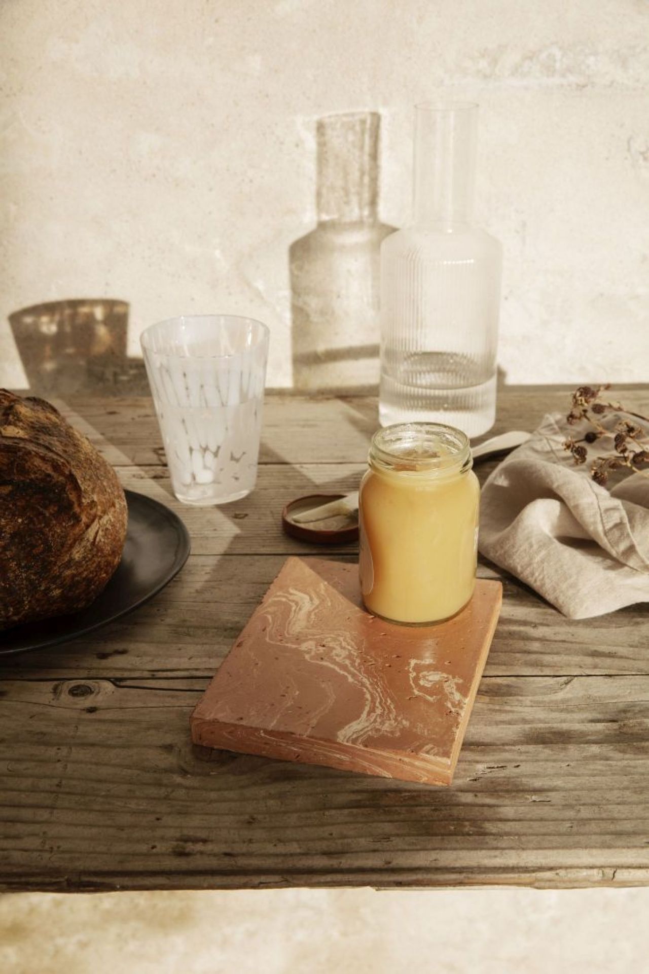 Merge Trivet Untersetzer von Ferm Living mit Marmormuster, darauf ein Glas Honig auf einem Holztisch.