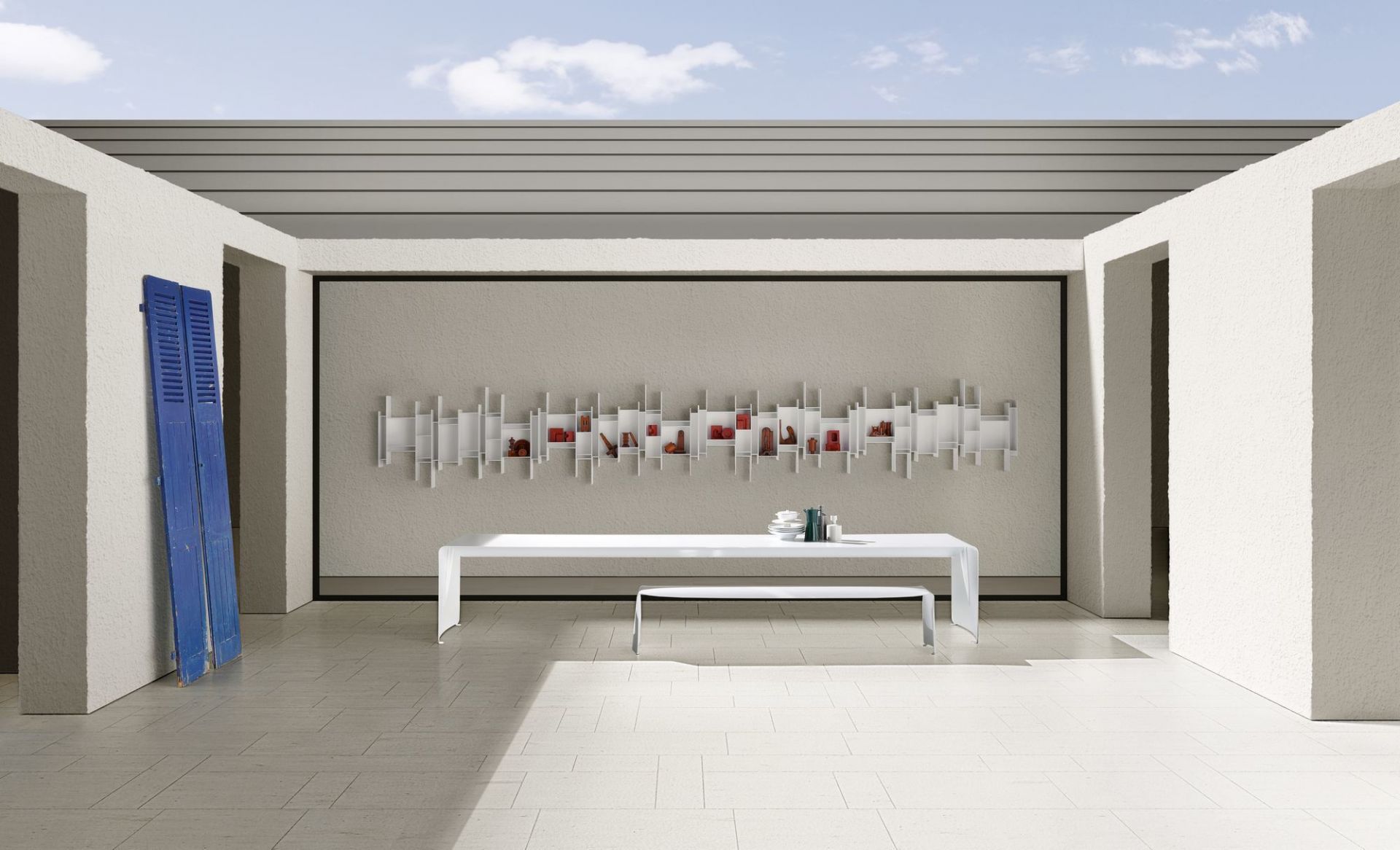 Weißes Randomito Regalsystem von MDF Italia an der Wand über einem weißen Tisch.