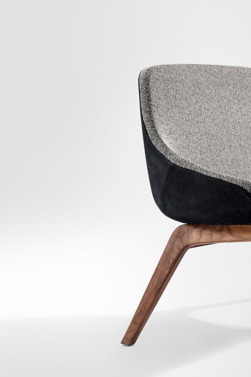 Detailansicht: Morph Dining Sofa mit grauem Stoff, schwarzem Leder und Holzfuß.