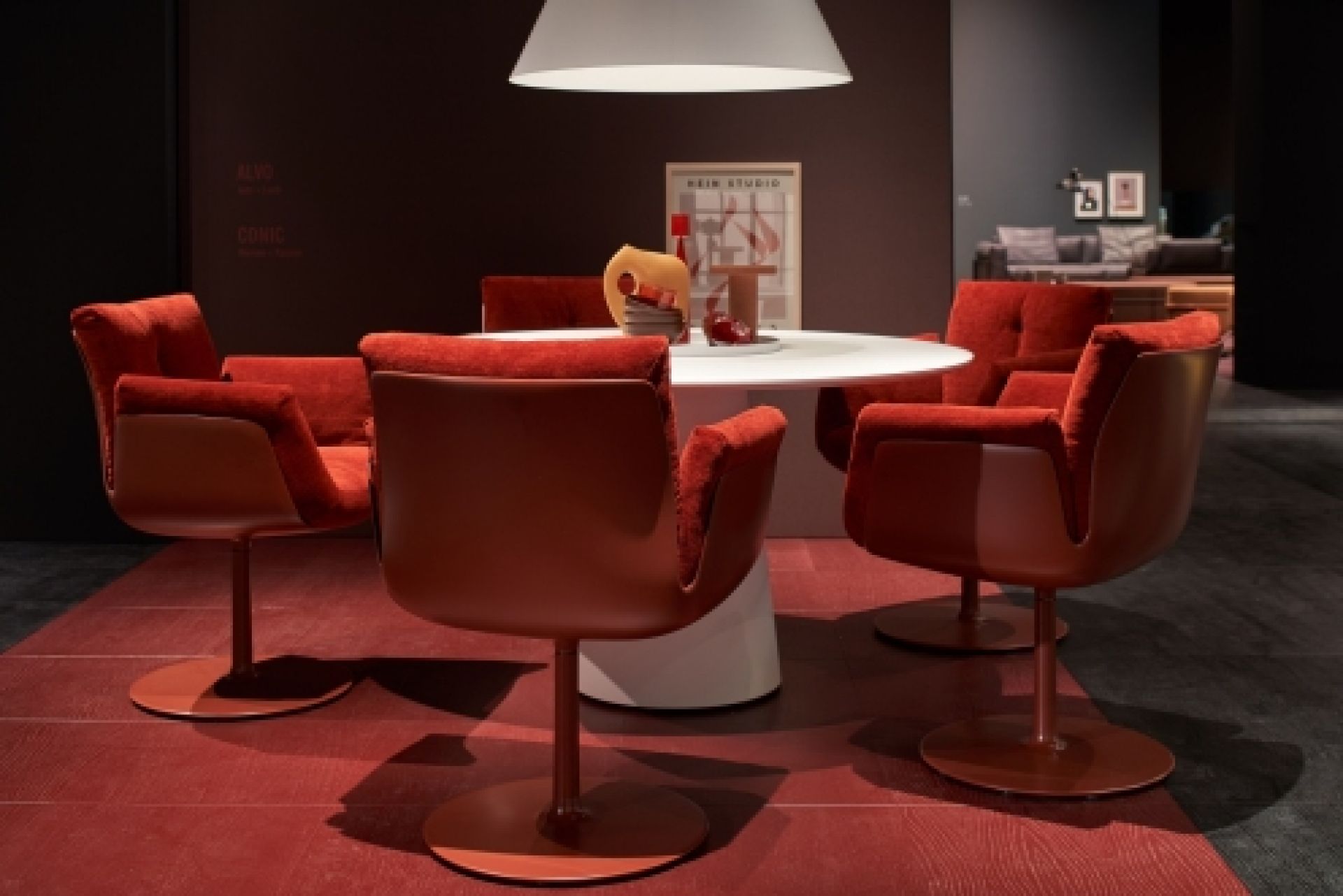 Rote Alvo Armlehnstühle mit Tellerfuß um einen weißen Esstisch, modernes Möbeldesign.