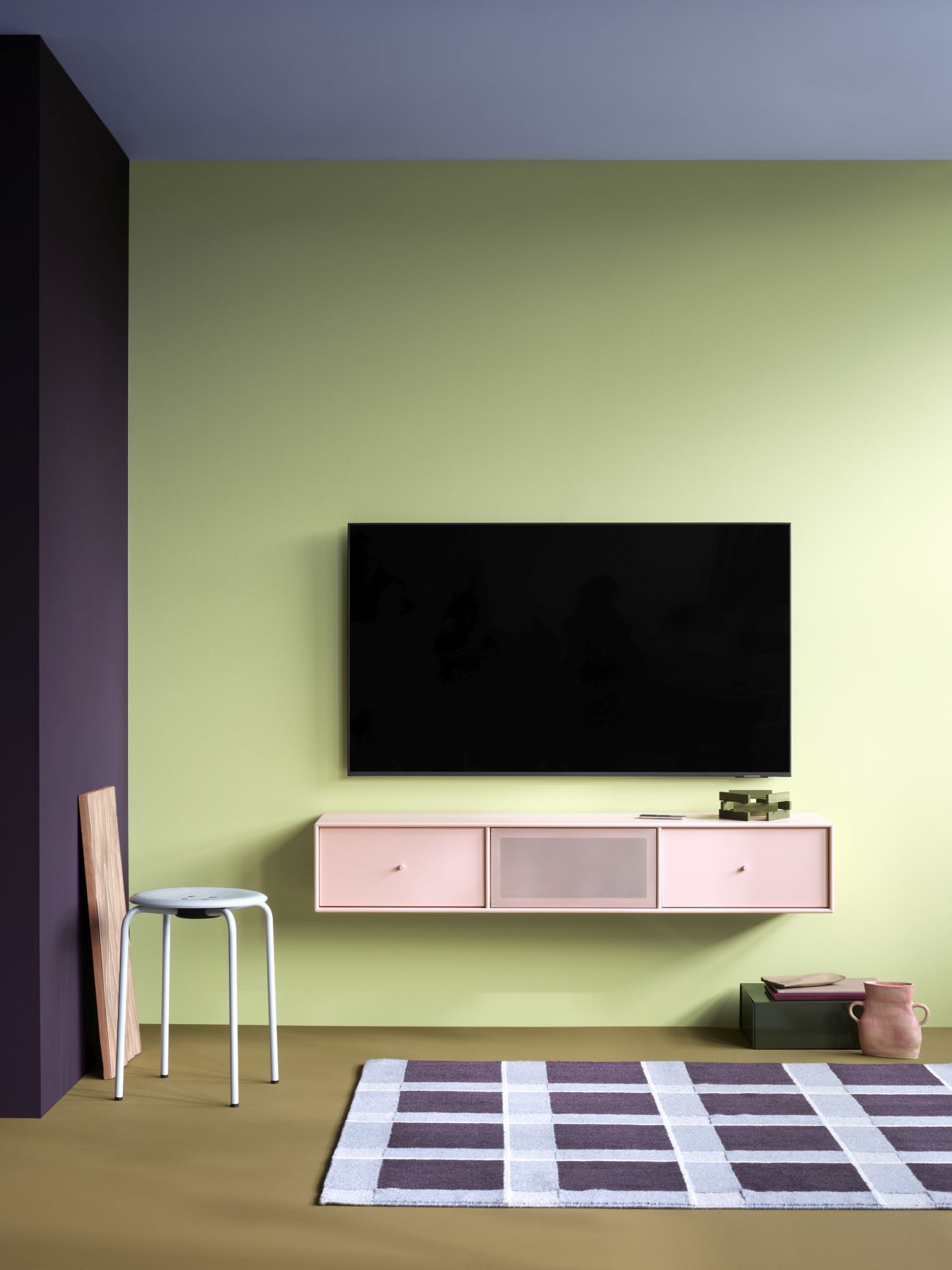 Octave V TV-Bank Fennel in Rosa mit schwarzem Gestell unter einem Fernseher an grüner Wand.