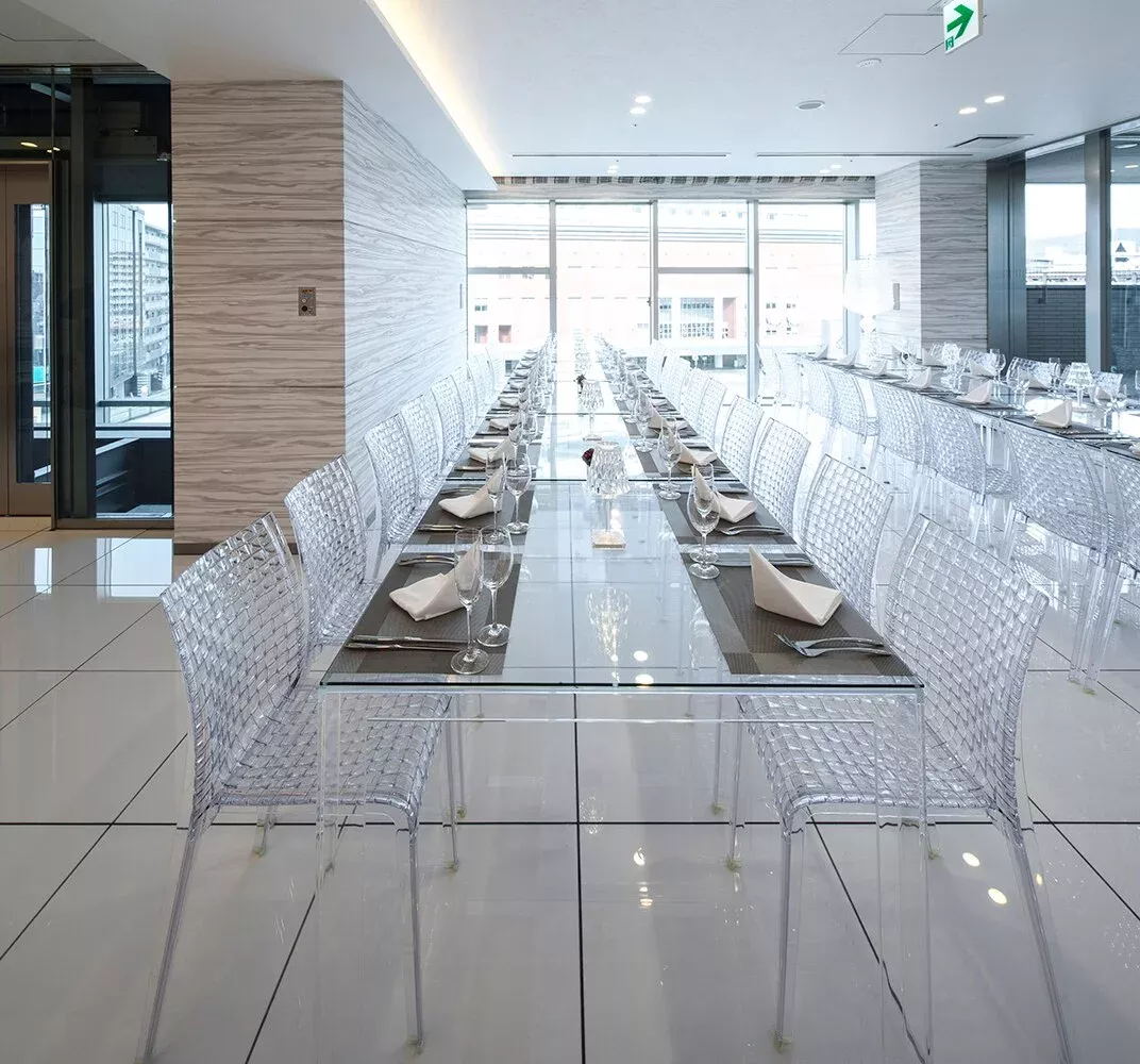 Langer Tisch mit vielen transparenten Ami Ami Stühlen von Kartell für eine Veranstaltung.