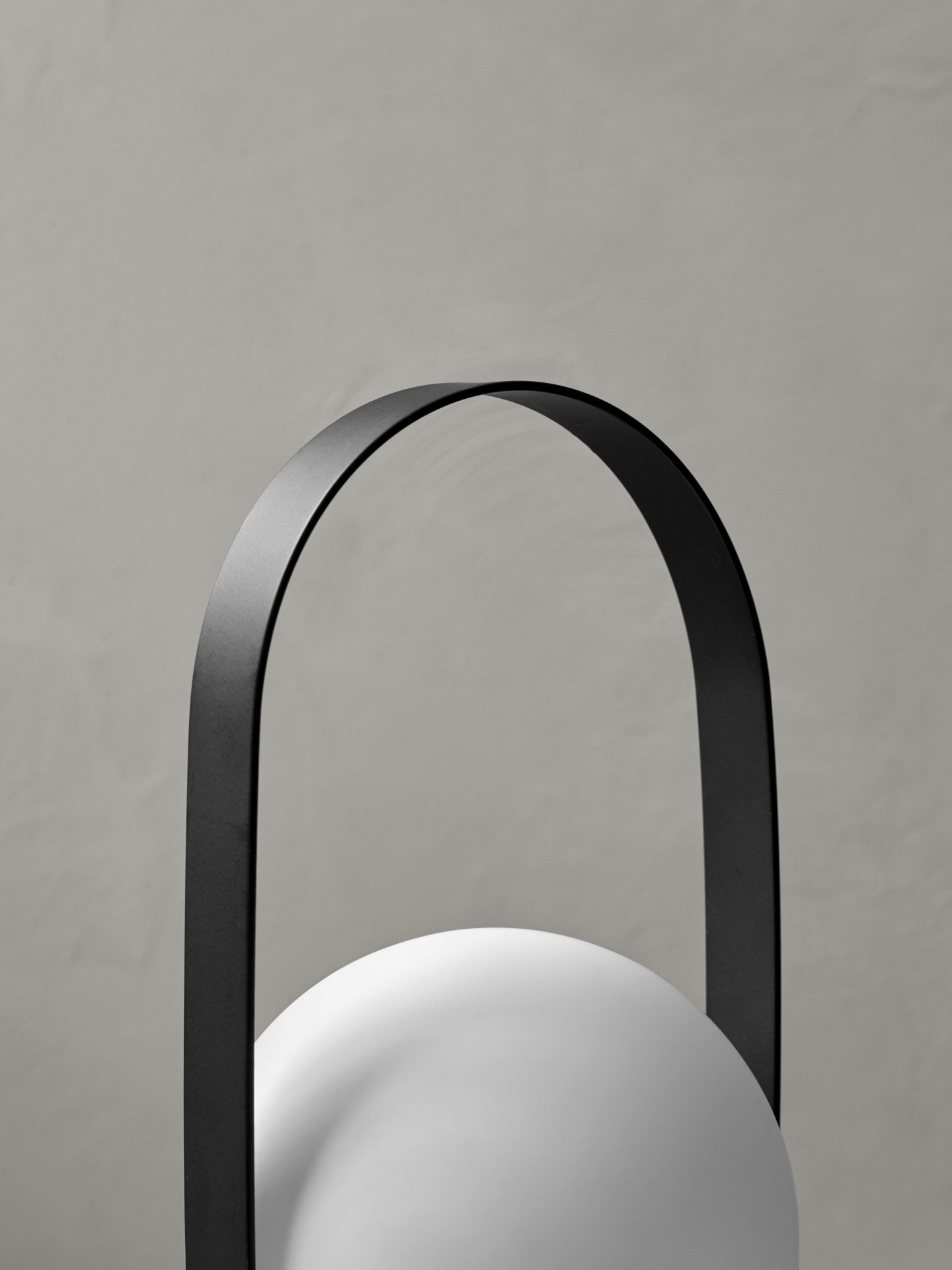 Detailaufnahme der Carrie Tischleuchte: Weiße Kugel mit schwarzem Tragebügel, tragbare Akkuleuchte.