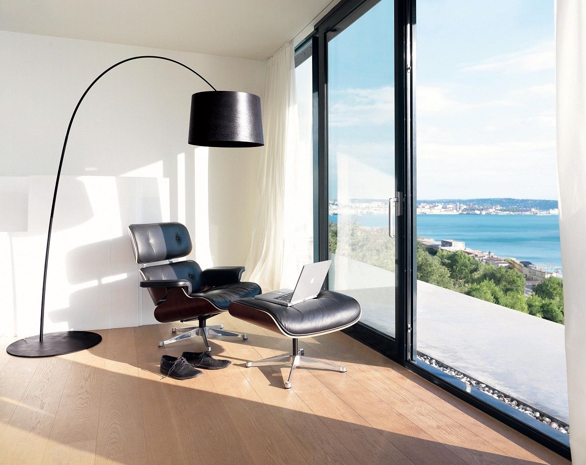 Moderne Twiggy Stehleuchte von Foscarini in Grau-Beige neben Sessel mit Meerblick im hellen Wohnzimmer.