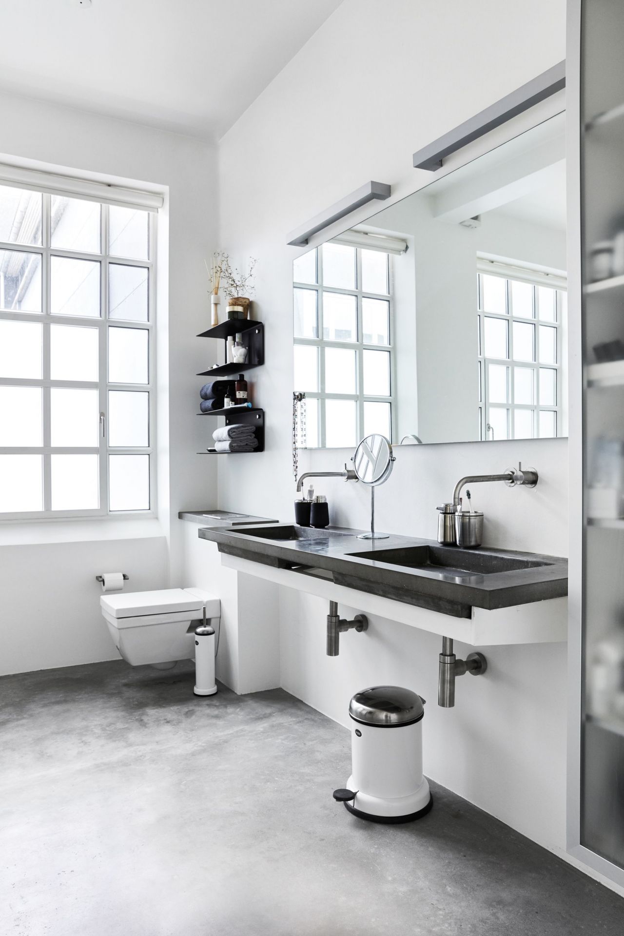 Helle Badezimmer-Szene mit weißer Wandtoilette und Vipp WC-Bürste in passendem Design neben der Toilette.