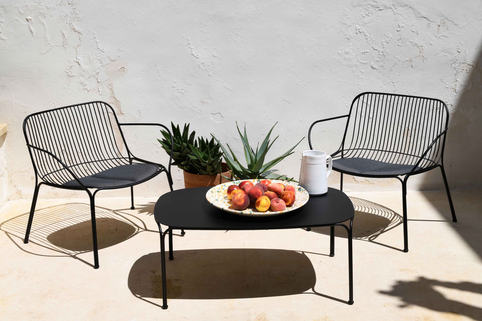 Zwei schwarze Hiray Stühle von Kartell mit Kissen und Tisch im Außenbereich.