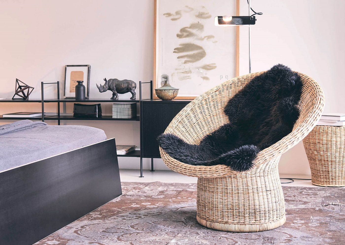 E10 Rattansessel von Richard Lampert mit schwarzem Schaffell in modernem Schlafzimmer. Rattanmöbel für stilvolles Wohnen.