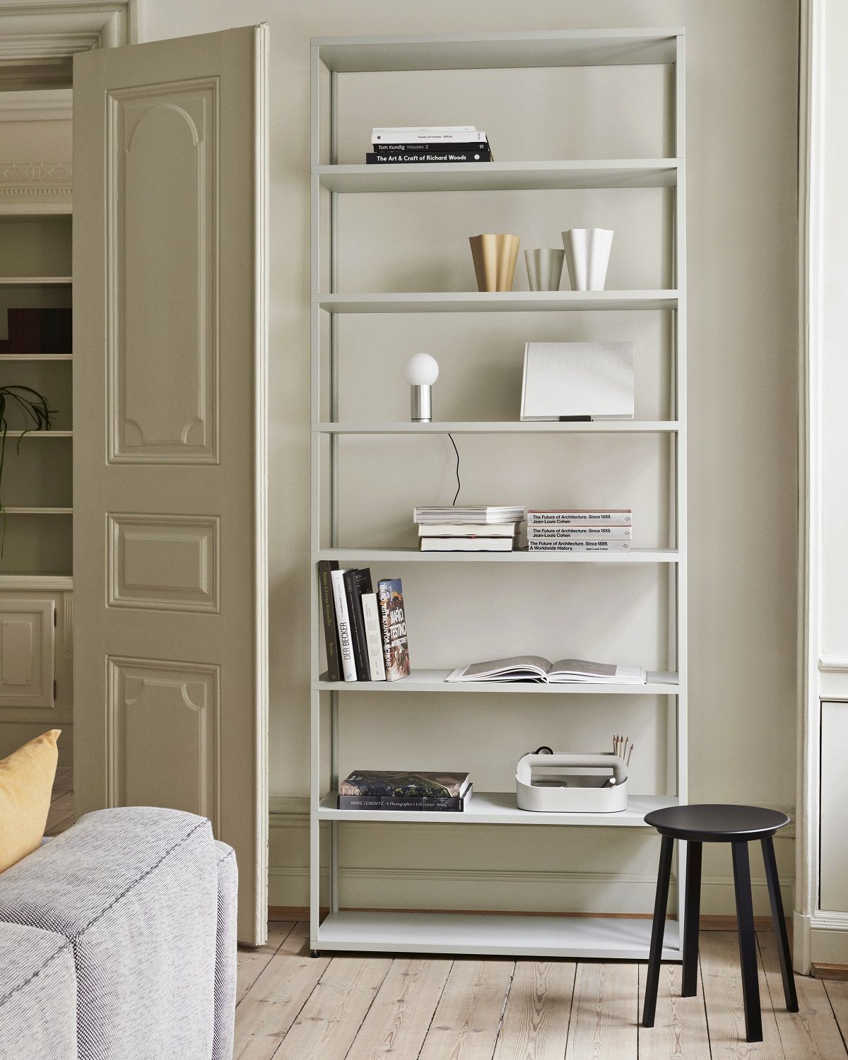 Schwarzer Revolver Stool Hocker von Hay vor einem Bücherregal in einem modern eingerichteten Wohnzimmer.