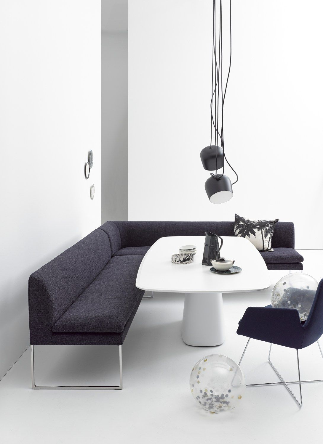 Elegante, dunkelgraue Mell Polsterbank von Cor mit Metallgestell und weißem Esstisch in modernem Interieur.