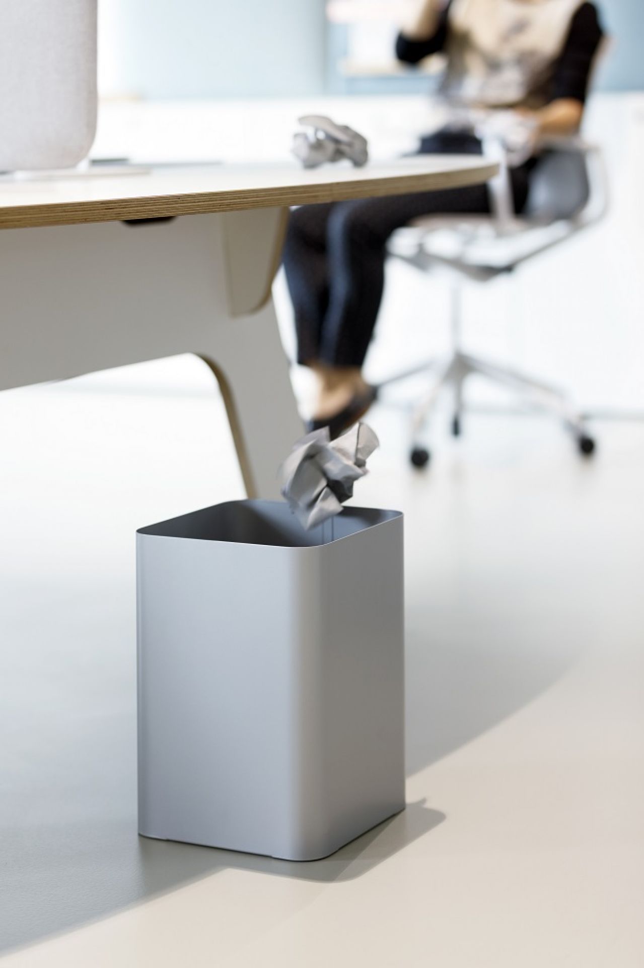 Grauer Cascando Flow II Papierkorb im Büro, Papier wird hineingeworfen. Moderner Abfalleimer für Büromöbel.