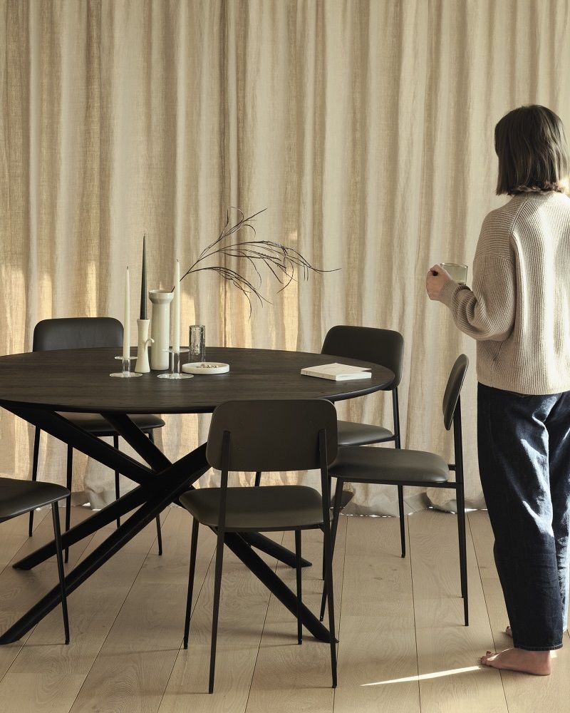 Ethnicraft Mikado Tisch: Runder Esstisch aus Eiche mit schwarzem Gestell und Stühlen.