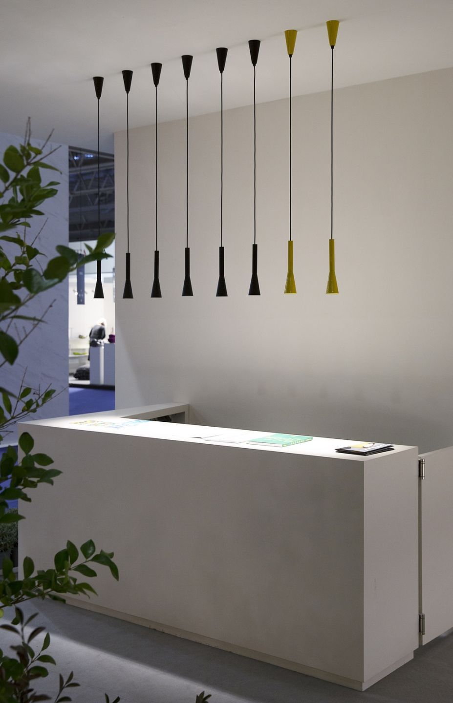 Colibrì Pendelleuchten von Martinelli Luce in Schwarz und Gelb über einem weißen Empfangstresen.