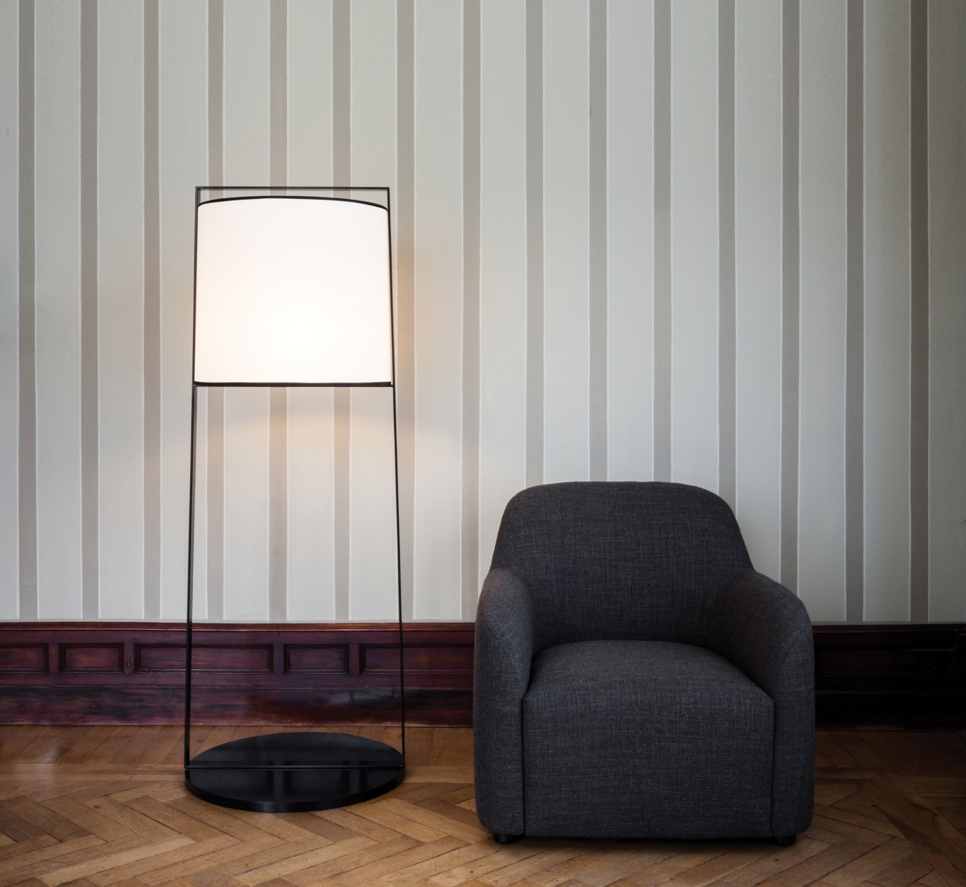 Moderne Tooy Stehleuchte Macao mit rechteckigem Lampenschirm und schwarzem Gestell neben Sessel.