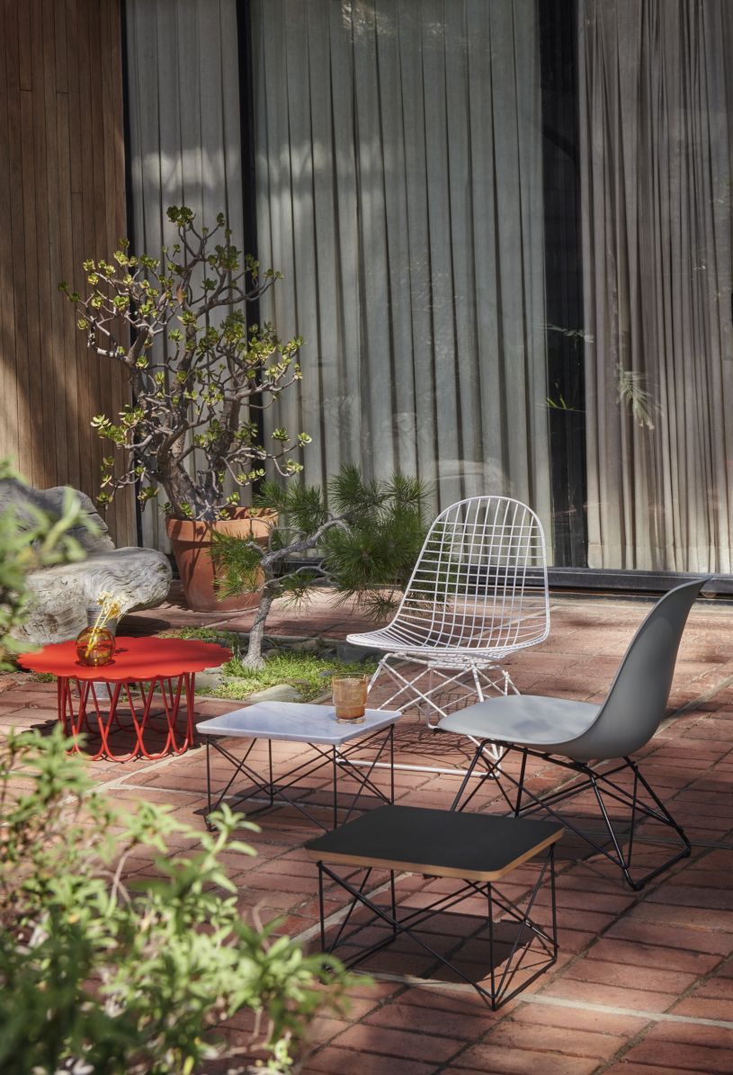 Eames Stuhl von Vitra: Grauer Fiberglass Chair LSR mit Drahtgestell und Beistelltischen im Garten.