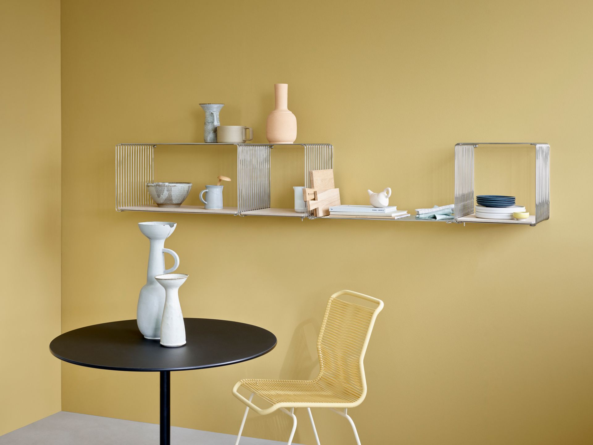 Glasboden im Wire Cube Regal von Montana, mit Deko-Elementen auf gelbem Hintergrund.