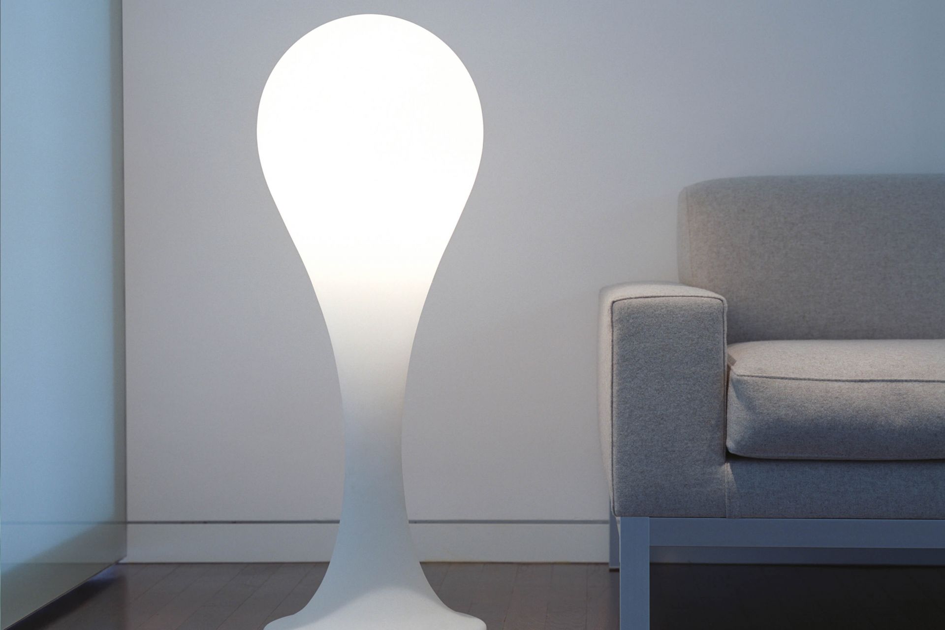 Helle Liquid Light Drop Standleuchte von Next neben einem grauen Sofa im modernen Wohnzimmer.