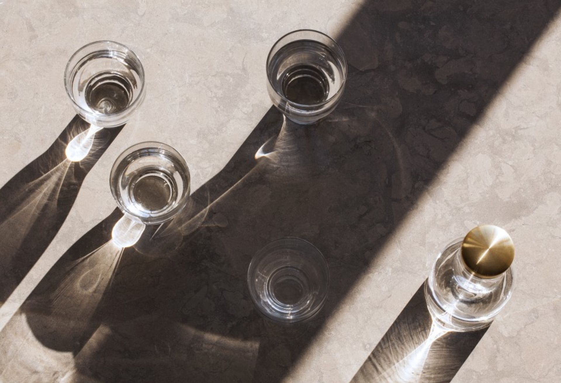 Bottle Collection Wasserkaraffe mit Gläsern im Sonnenlicht. Elegante Glaskaraffe und Trinkgläser für Wasser.