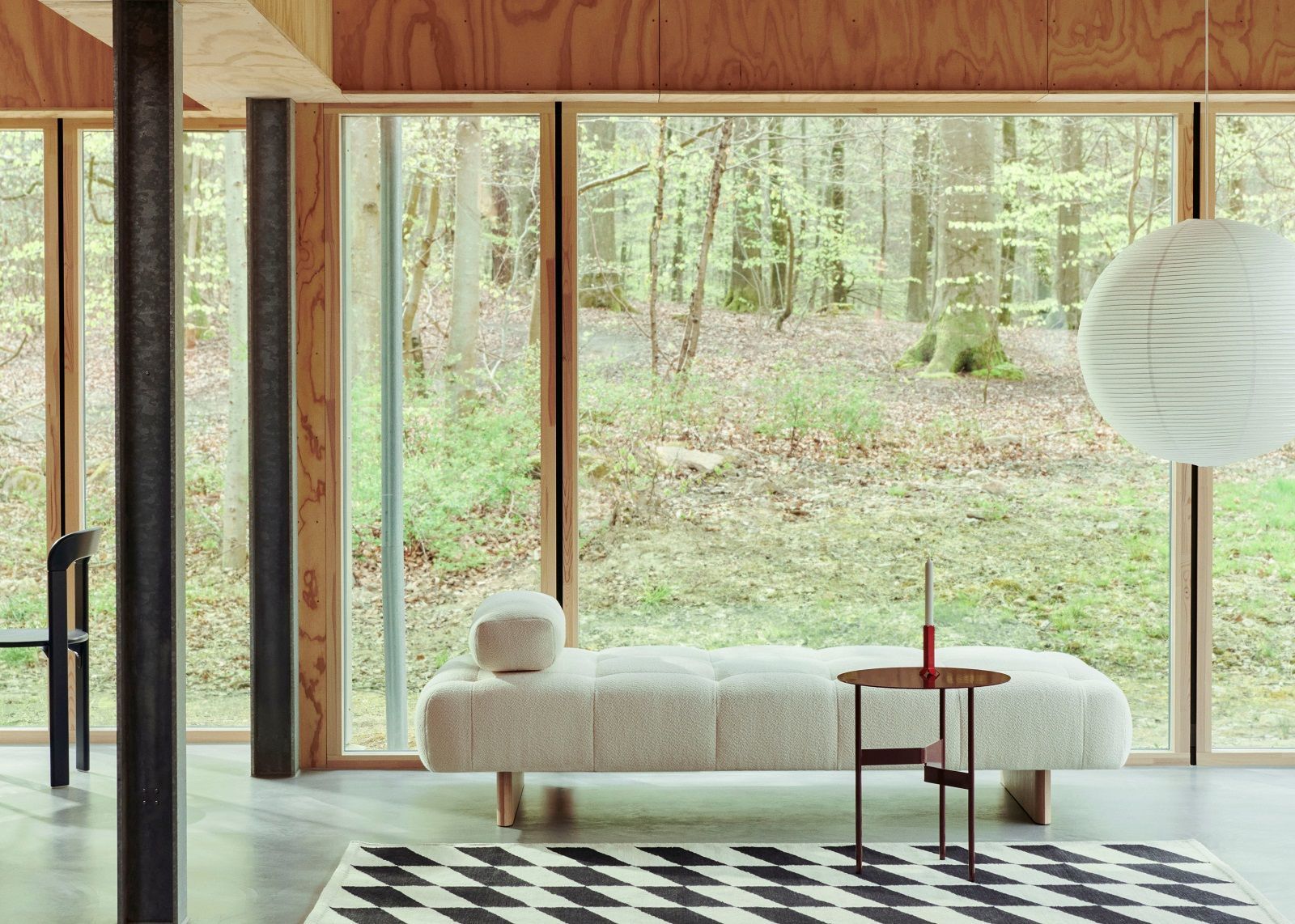 Wohnzimmer mit Hay Beistelltisch Shim Table, Sofa, Teppich und Blick in den Wald.