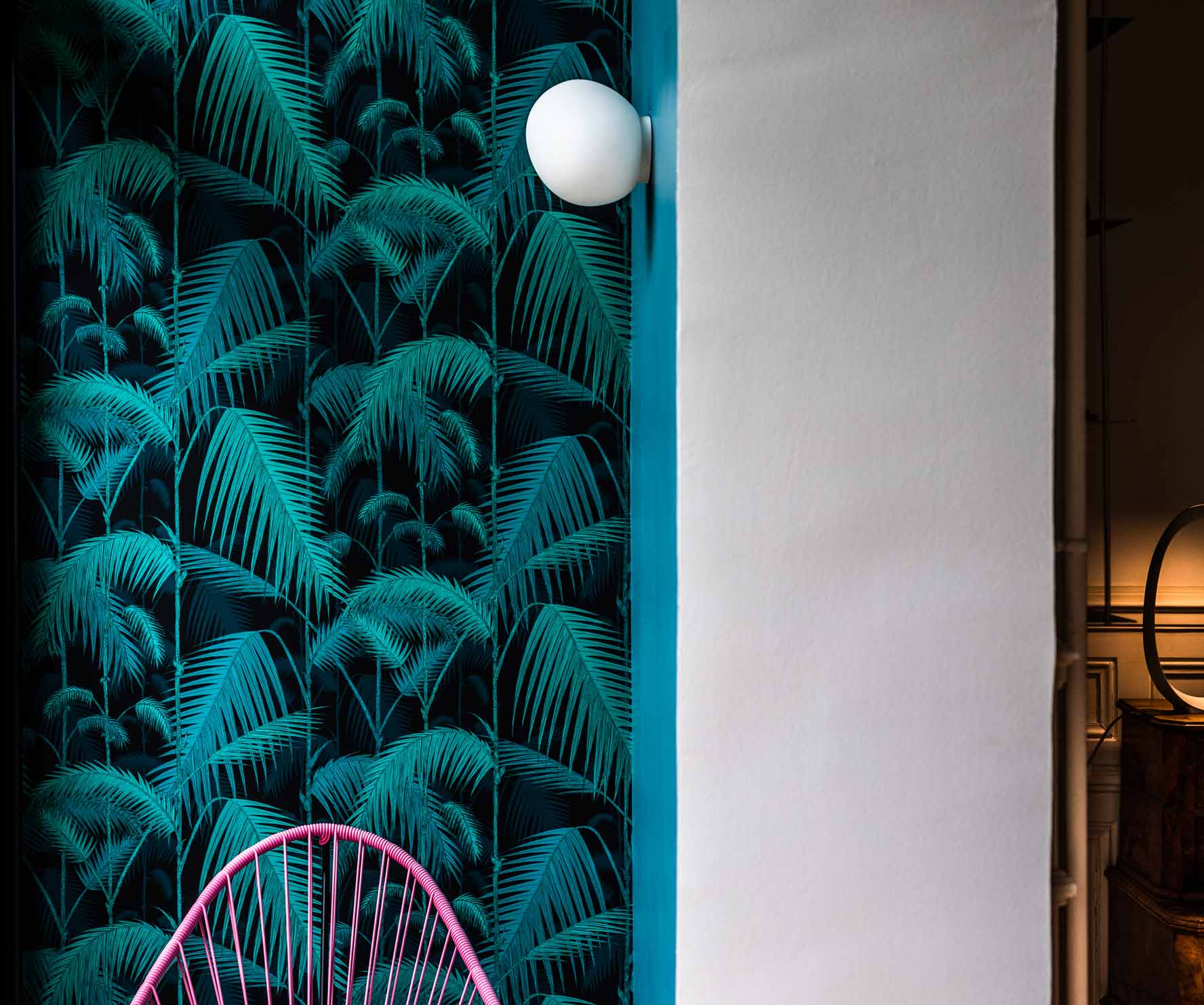 Weiße Gregg Wandleuchte von Foscarini an Wand mit tropischem Palmenmuster, moderne Innenbeleuchtung.