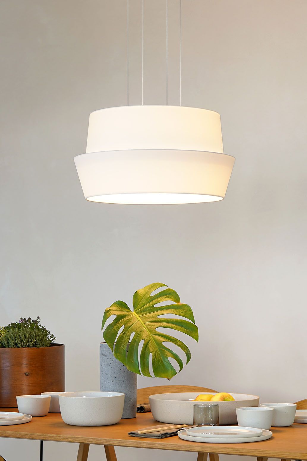 Weiße Fly Pendelleuchte von Maigrau über Esstisch mit Geschirr und Pflanzendekoration.
