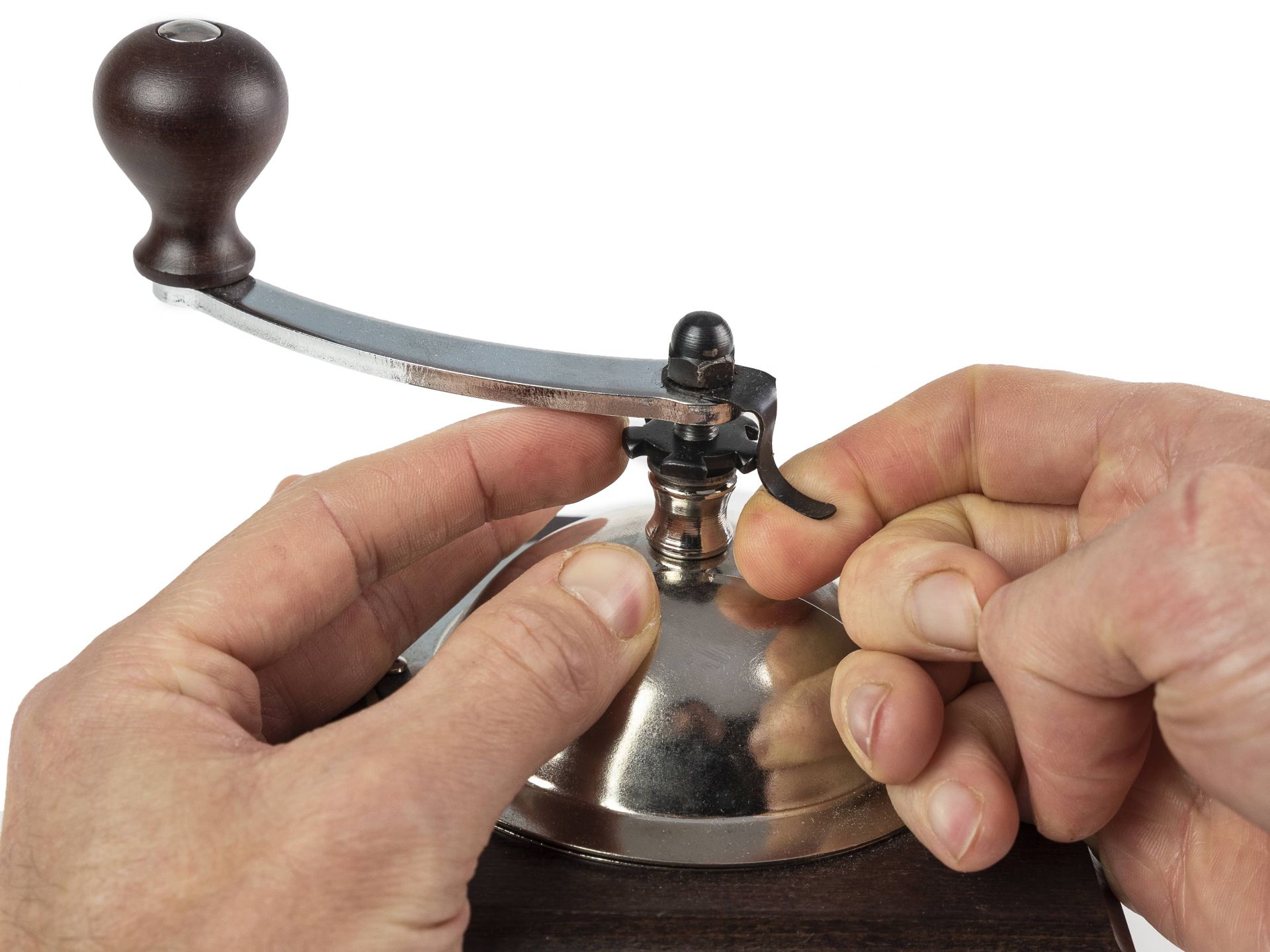 Hände bedienen eine nostalgische Peugeot Kaffeemühle mit Kurbel zum Mahlen von Kaffeebohnen.