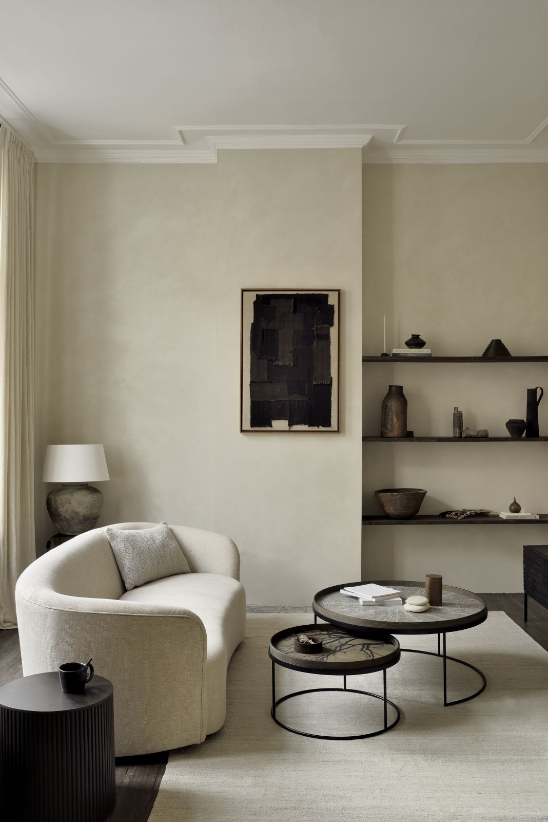 Wohnzimmer-Szene mit Ethnicraft Slice Tabletts, Couch, Regalen und Kunst an der Wand.