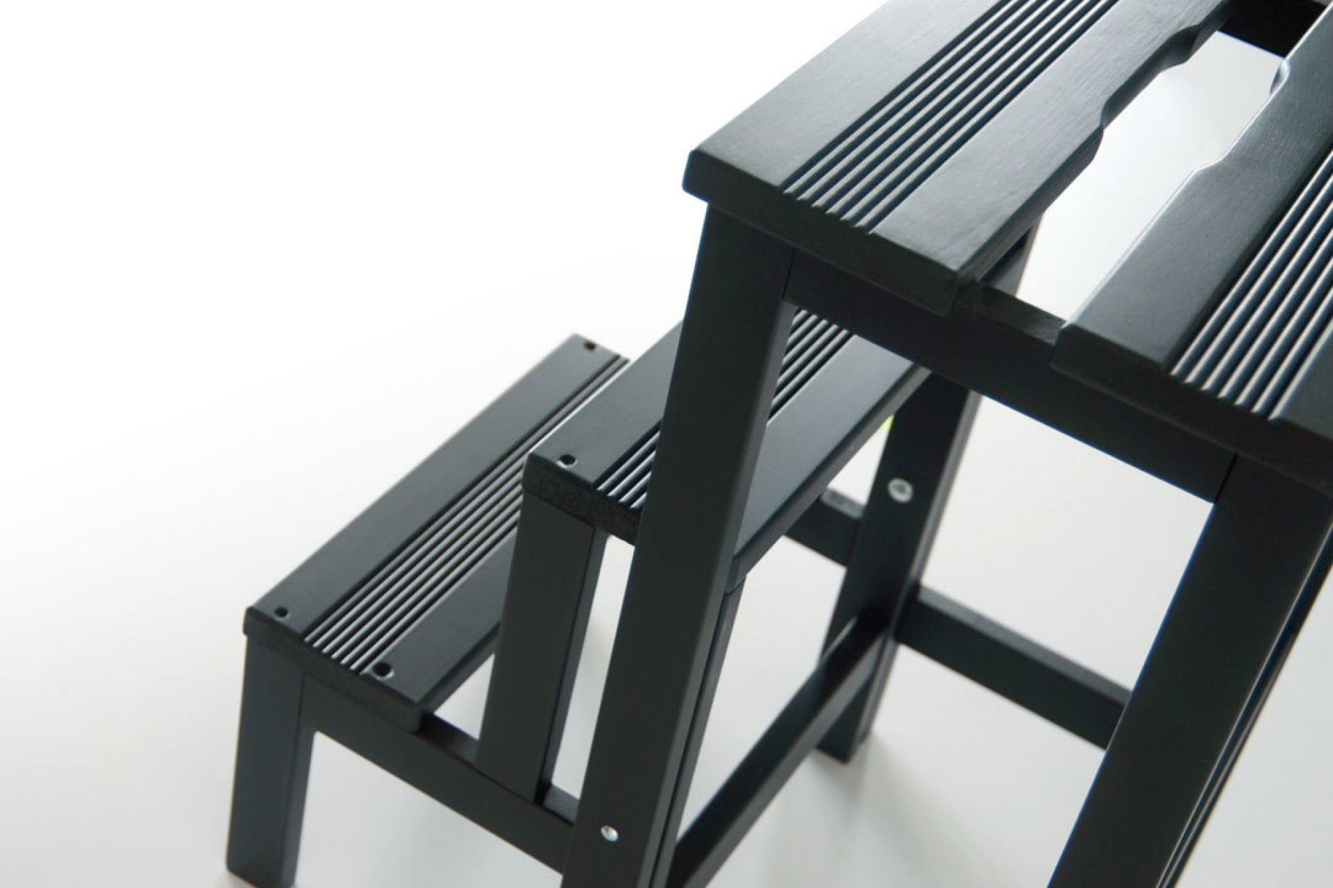 Nahaufnahme einer schwarzen Hockerleiter aus Holz mit zwei Stufen.