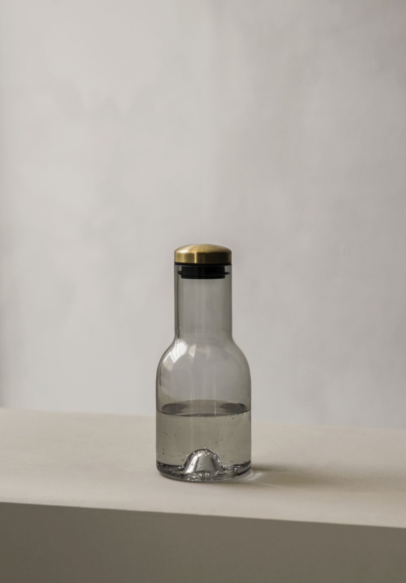 Graue 0,5 Liter Wasserkaraffe von Bottle Collection mit goldenem Deckel, gefüllt mit Wasser.