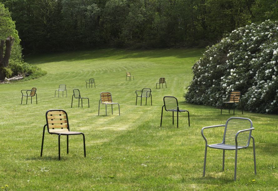 Mehrere Normann Copenhagen Vig Chair Wood Stühle im Freien auf einer grünen Wiese mit Bäumen im Hintergrund.