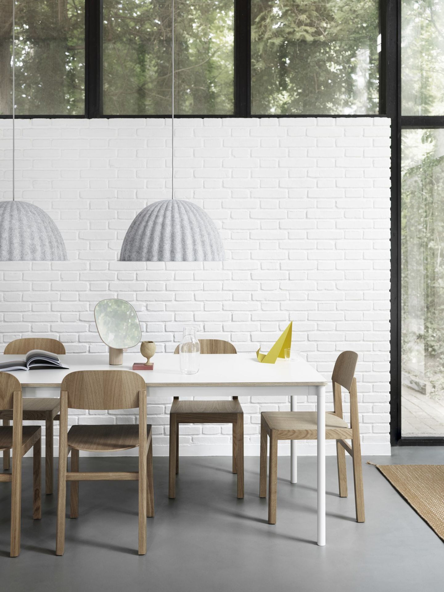 Esszimmer mit Esstisch, Holzstühlen und zwei grauen Under The Bell Pendelleuchten von Muuto.