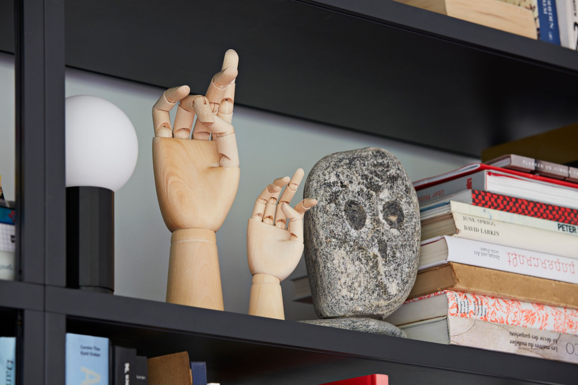 Dekorative Holzhand "Wooden Hand S Hay EINZELSTÜCK" und Steinskulptur auf einem Bücherregal.