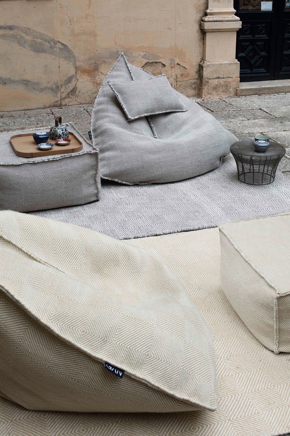 Sail Pouf Sitzsack Gan: Gemütliche Outdoor-Szene mit Sitzsäcken, Poufs und Teppichen in Beige und Grau.