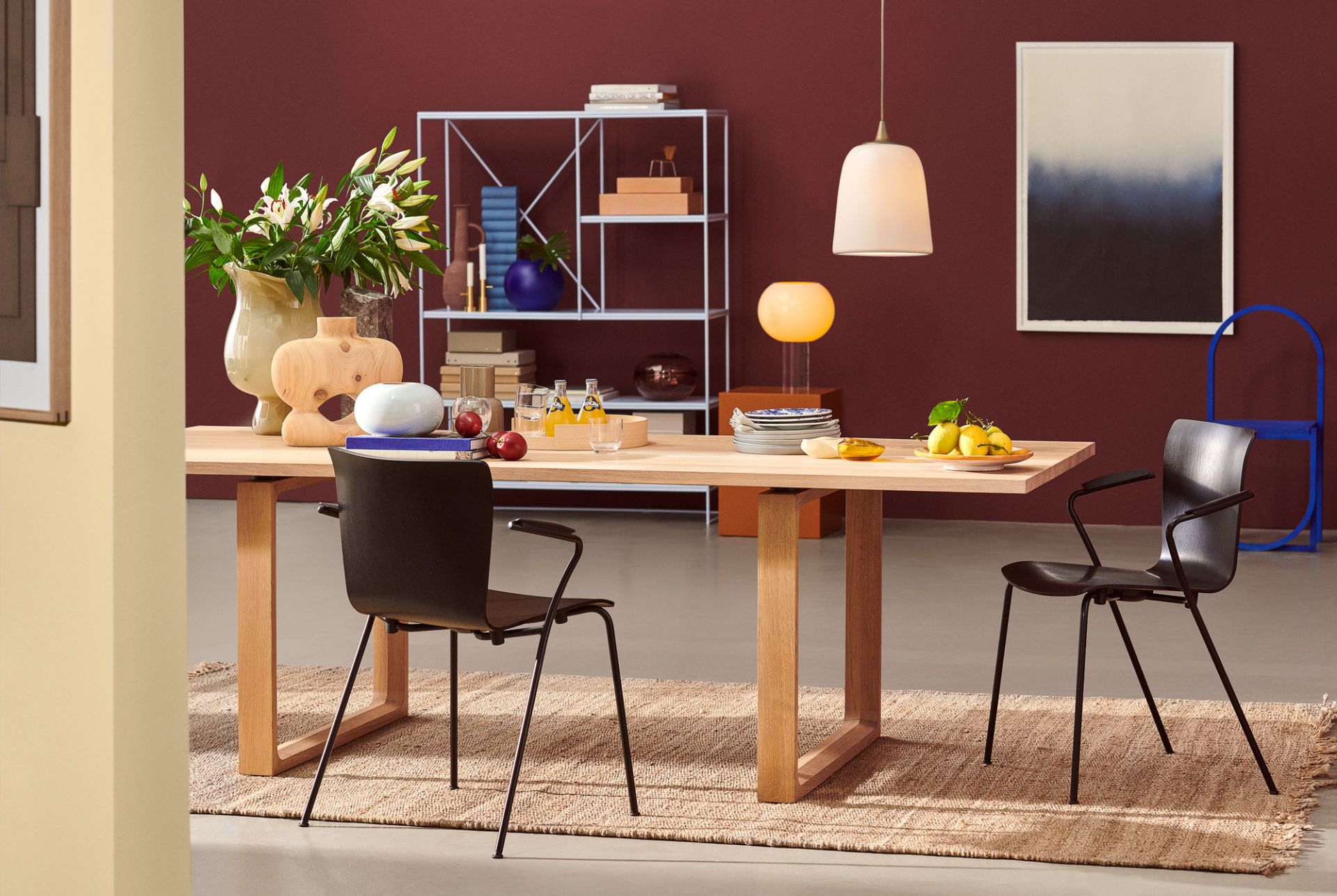 Esszimmer mit Holztisch, Teppich und zwei schwarzen Vico Stühlen von Fritz Hansen.