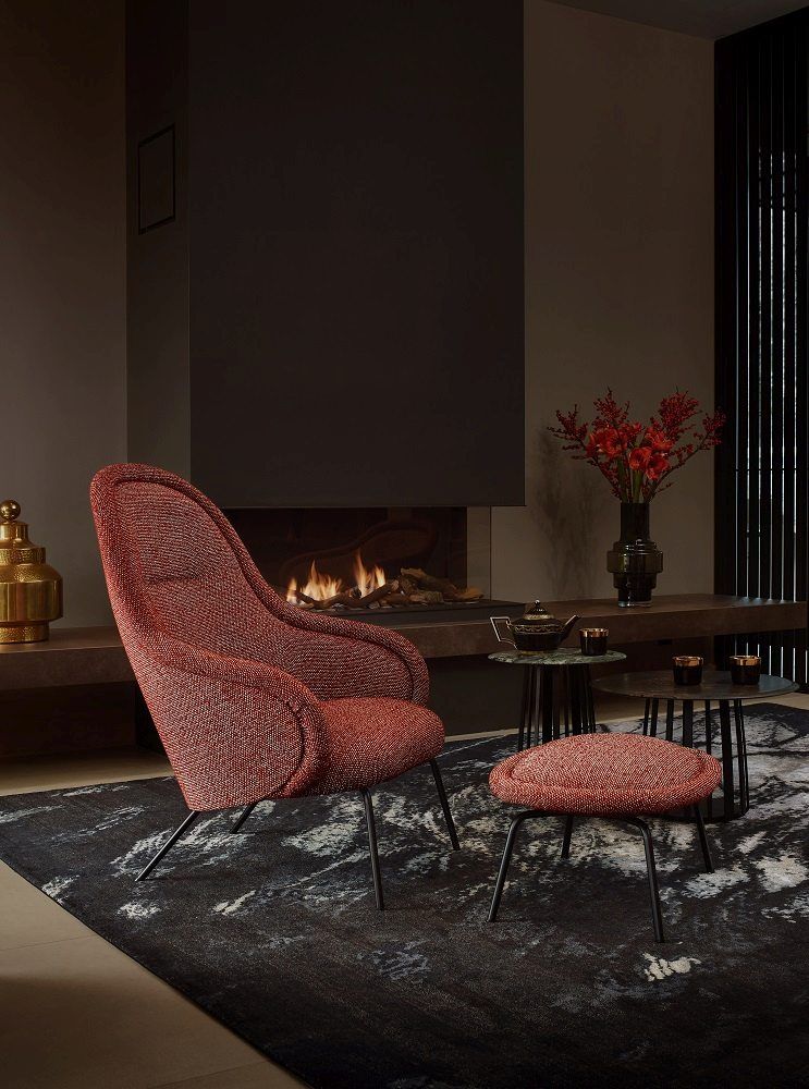 Ona Lounge Chair von Freifrau Manufaktur, roter Sessel mit Hocker vor Kamin.
