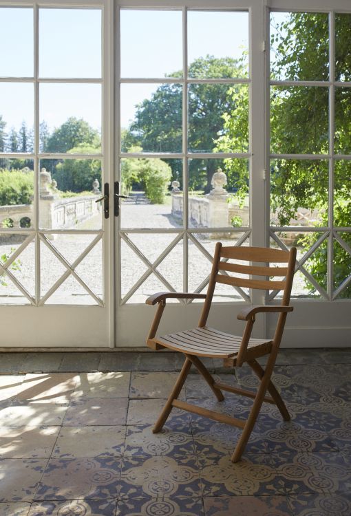 Selandia Armchair Sessel aus Teakholz von Skagerak by Fritz Hansen vor Terrassentür.