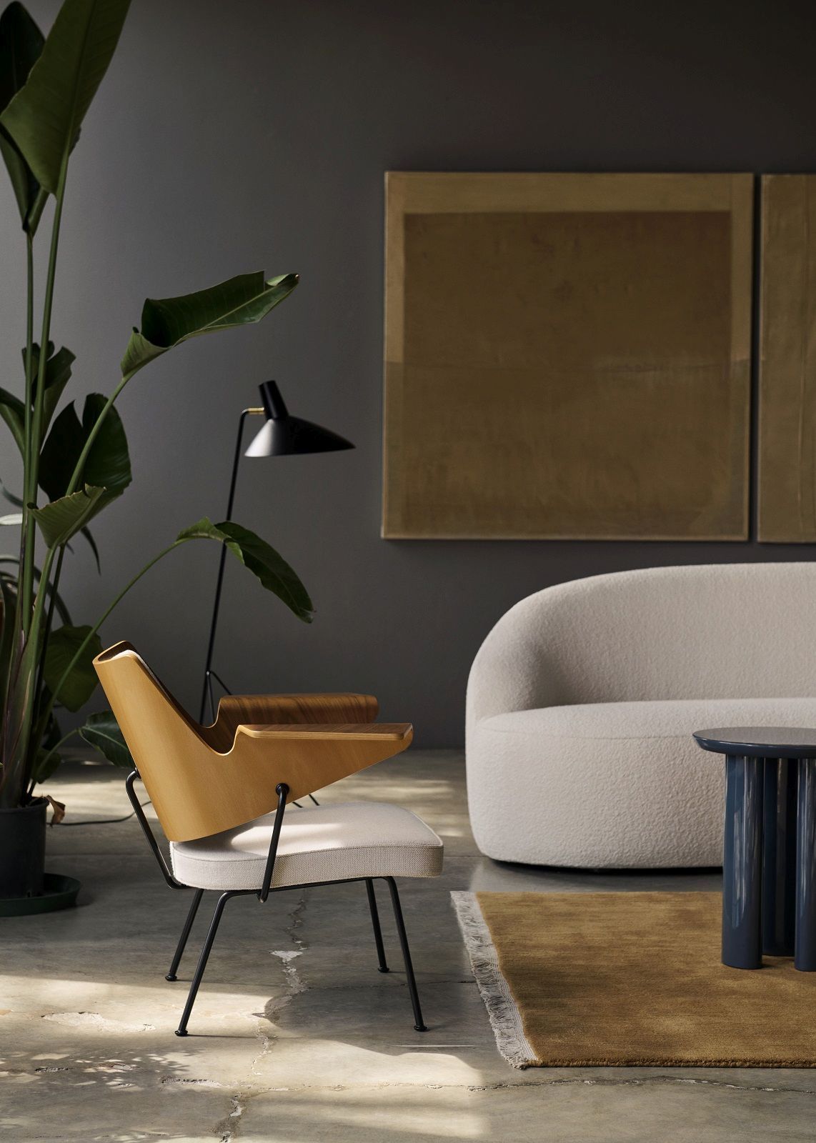 AndTradition Margas LC4 Sofa in hellem Bouclé-Stoff mit Sessel und Beistelltisch in Wohnraum.