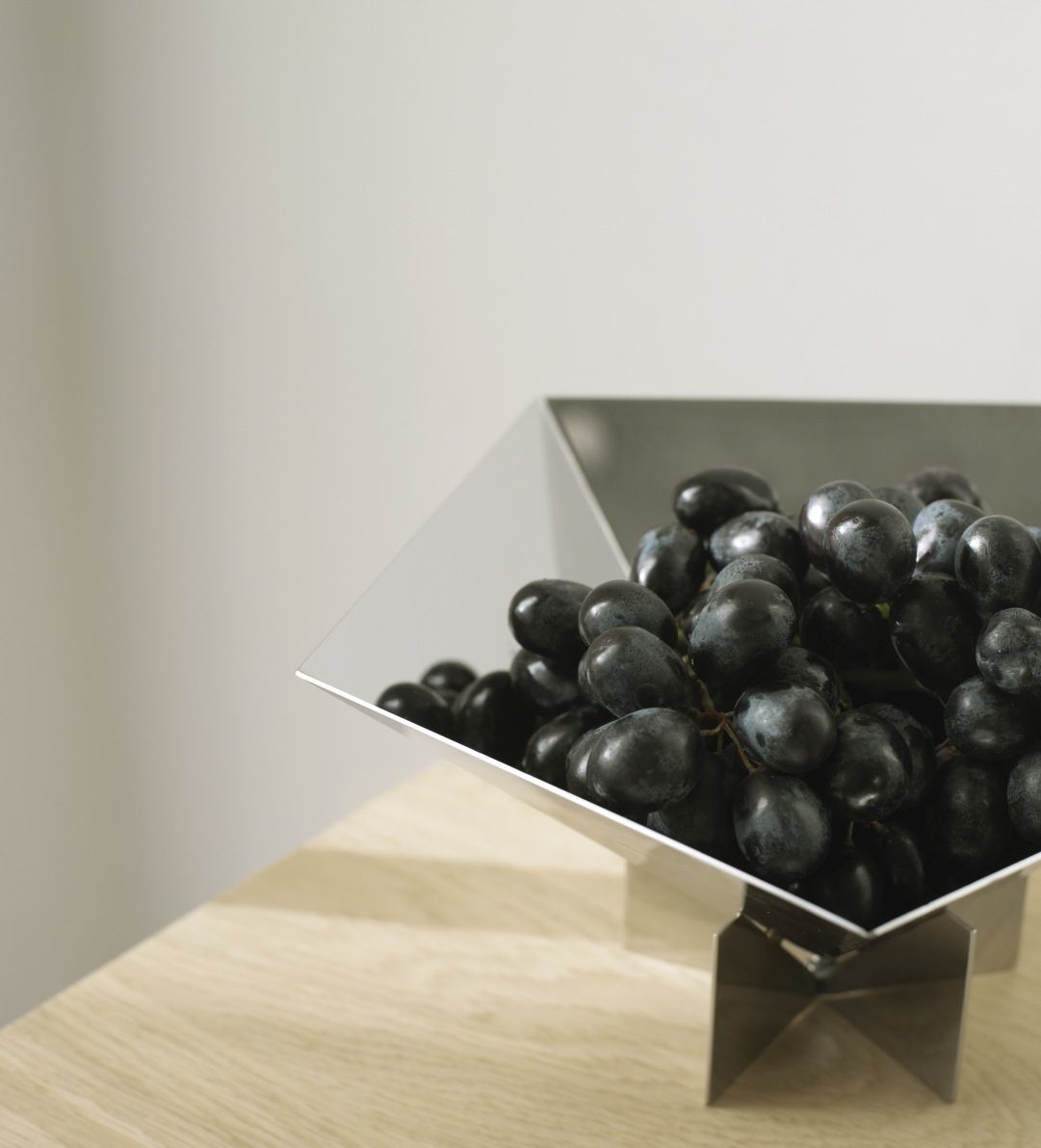 Nahaufnahme der Fem Schale von Normann Copenhagen aus Edelstahl, gefüllt mit dunklen Trauben.