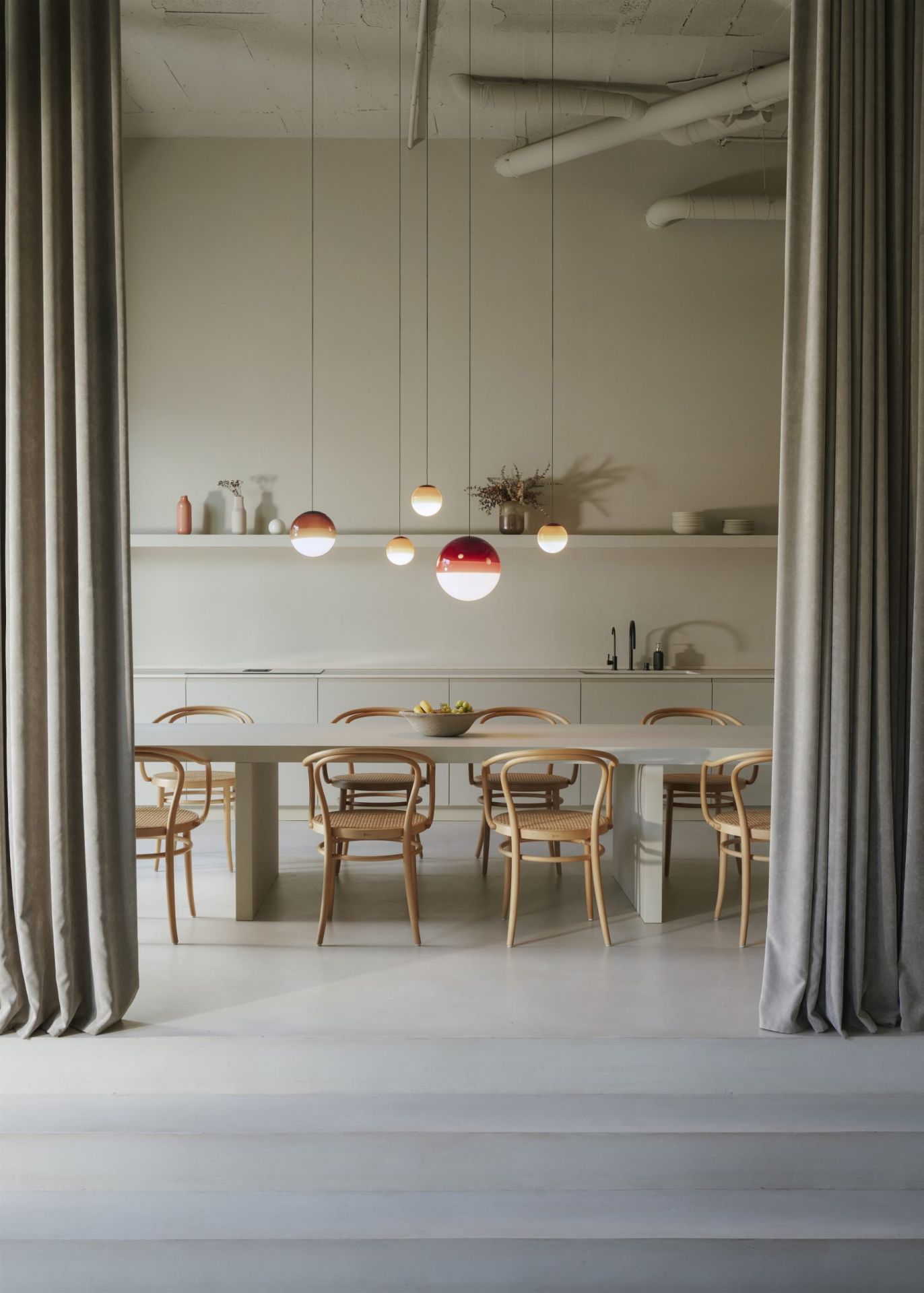 Esszimmer mit Esstisch und Marset Dipping Light Pendelleuchten in verschiedenen Farben und Größen über dem Tisch.