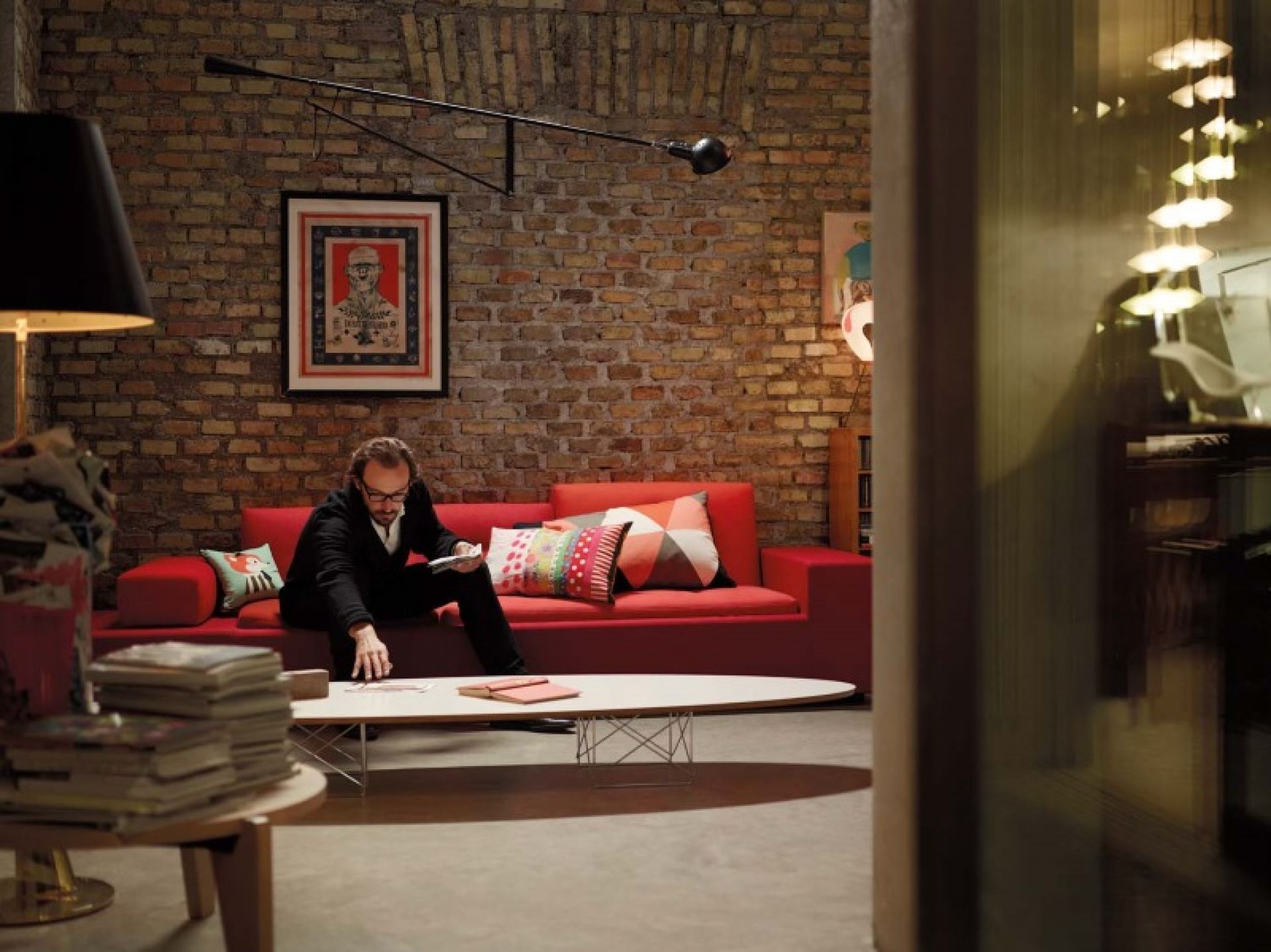 Wohnzimmer mit Gueridon Tisch von Vitra, rotem Sofa und Person. Designermöbel für stilvolles Wohnen.