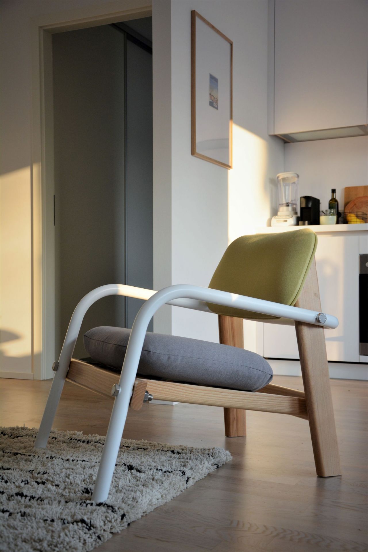 Billy Sessel von Jan Kurtz: Moderner Sessel mit weißem Gestell, grauem Kissen und grünem Sitz.