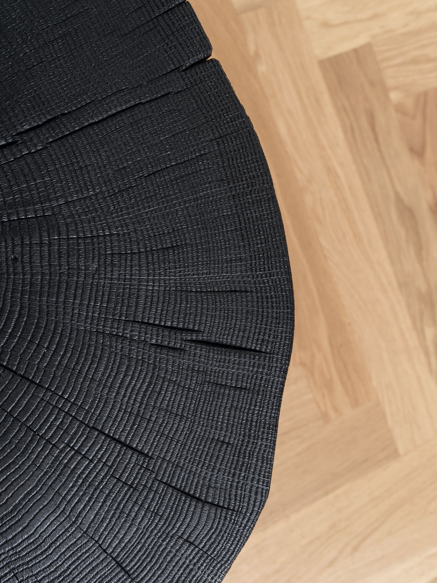 Detailaufnahme: Geköhlter Stomp Beistelltisch von Janua, H28. Schwarzer Holzhocker mit sichtbarer Maserung. Modernes Möbeldesign.