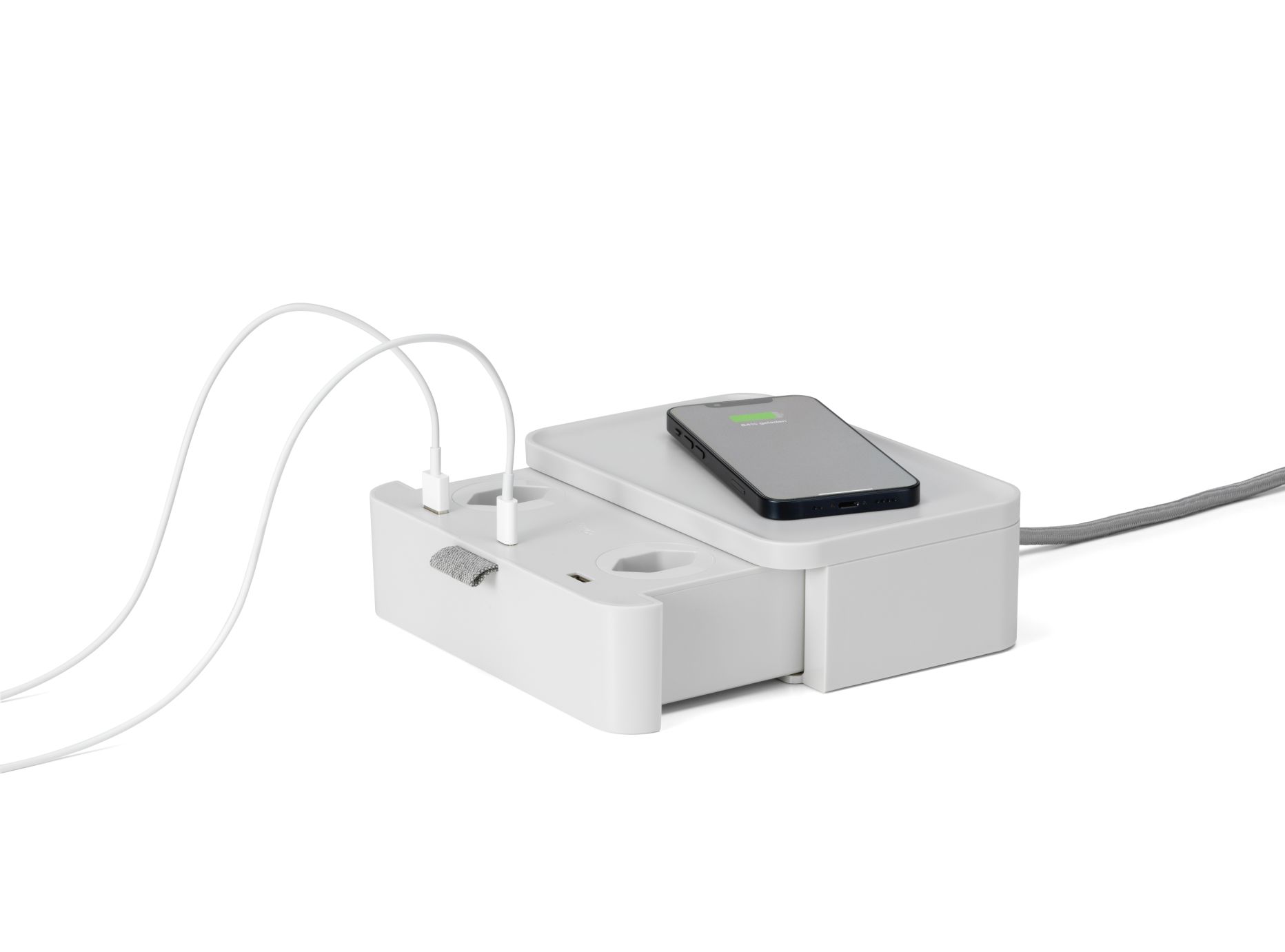 Ampi Wireless Charger und Mehrfachsteckdose von Vitra: Weißer Ladestation mit Steckdosen und aufladendem Smartphone.