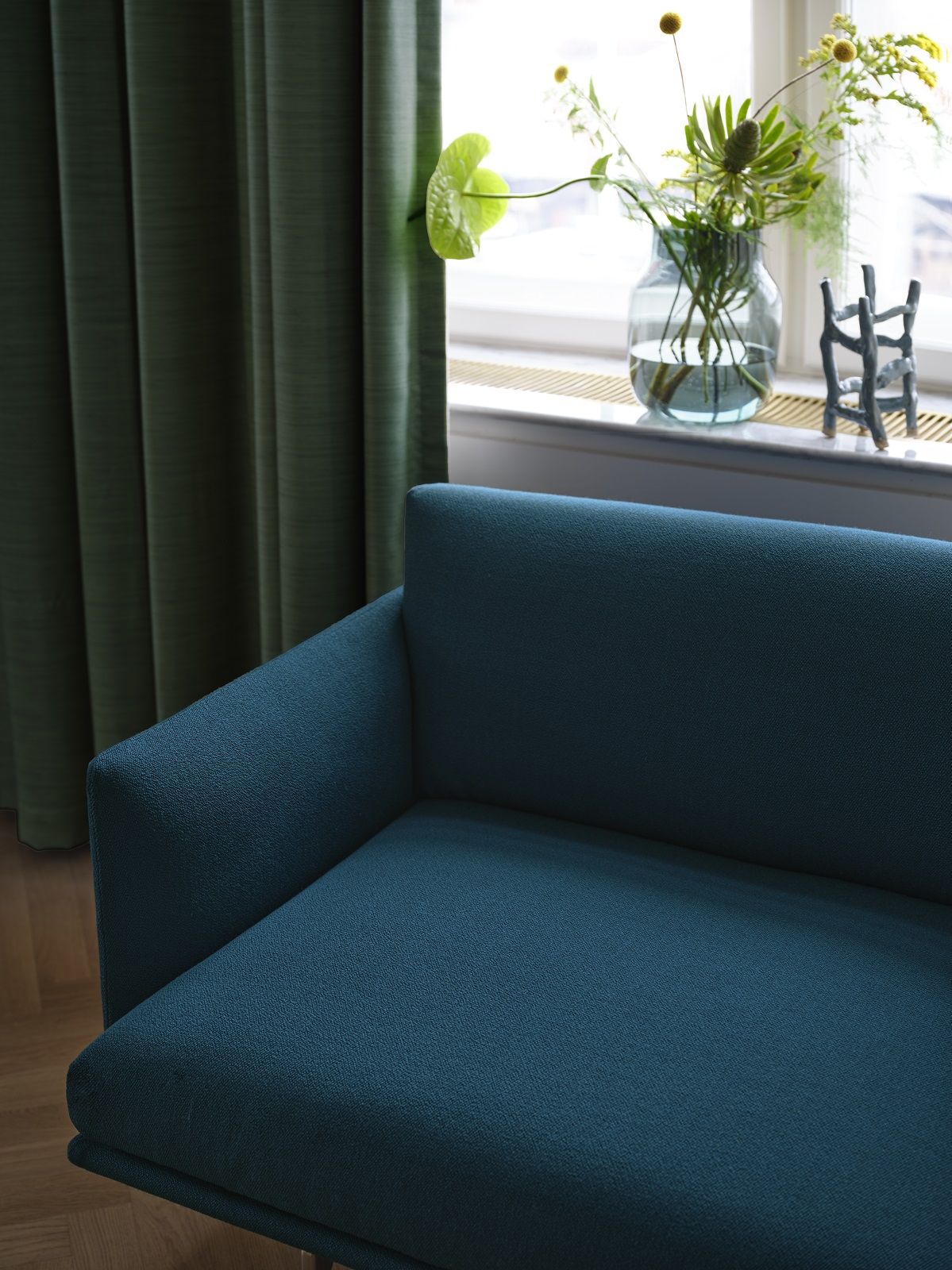 Nahaufnahme des Muuto Outline Studio Sofas in Türkis, vor einem Fenster mit Vorhängen.